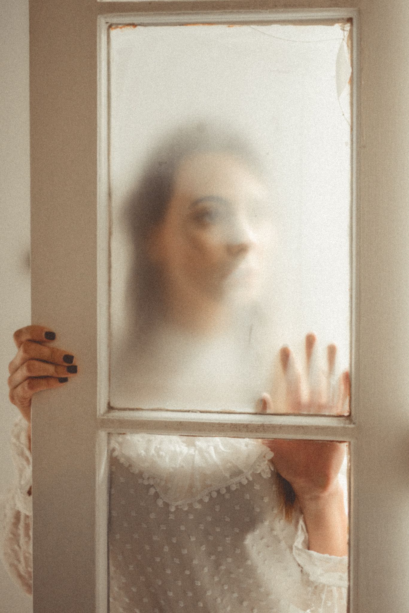 Mysterious silhouette behind frosted glass with hands pressed against the surface.