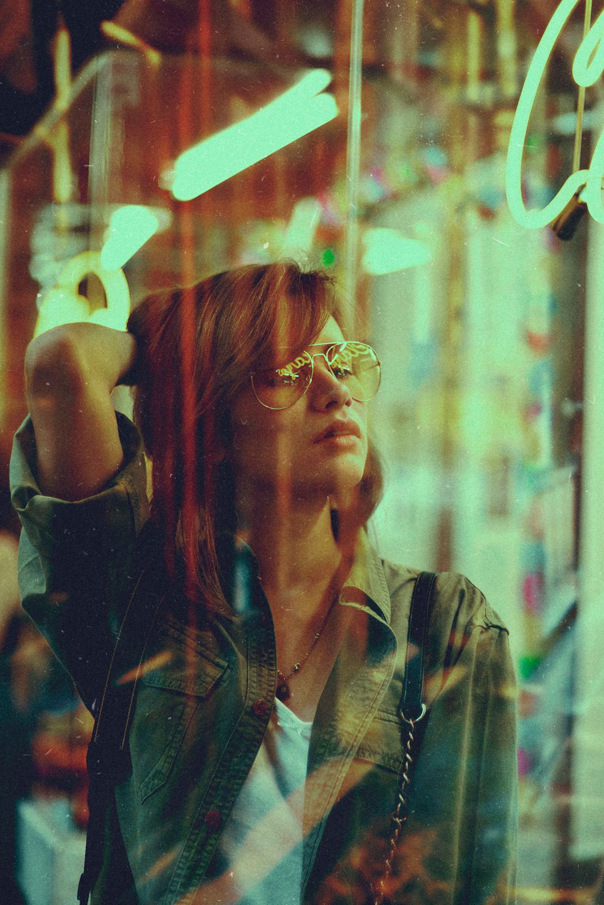 Retro-styled portrait with neon lights reflecting in glasses.