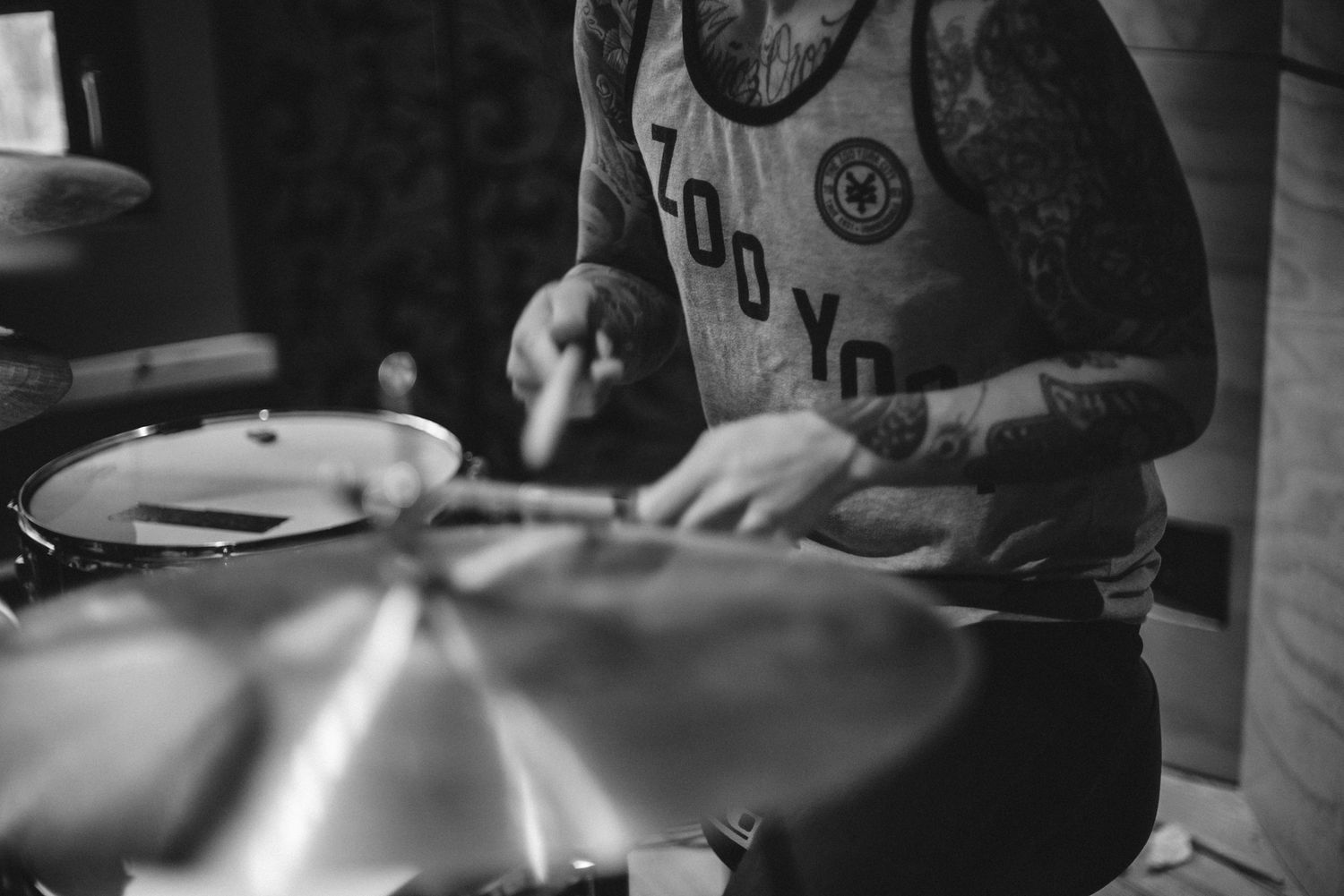 Close-up black and white shot of hands playing cymbals on a drum kit.