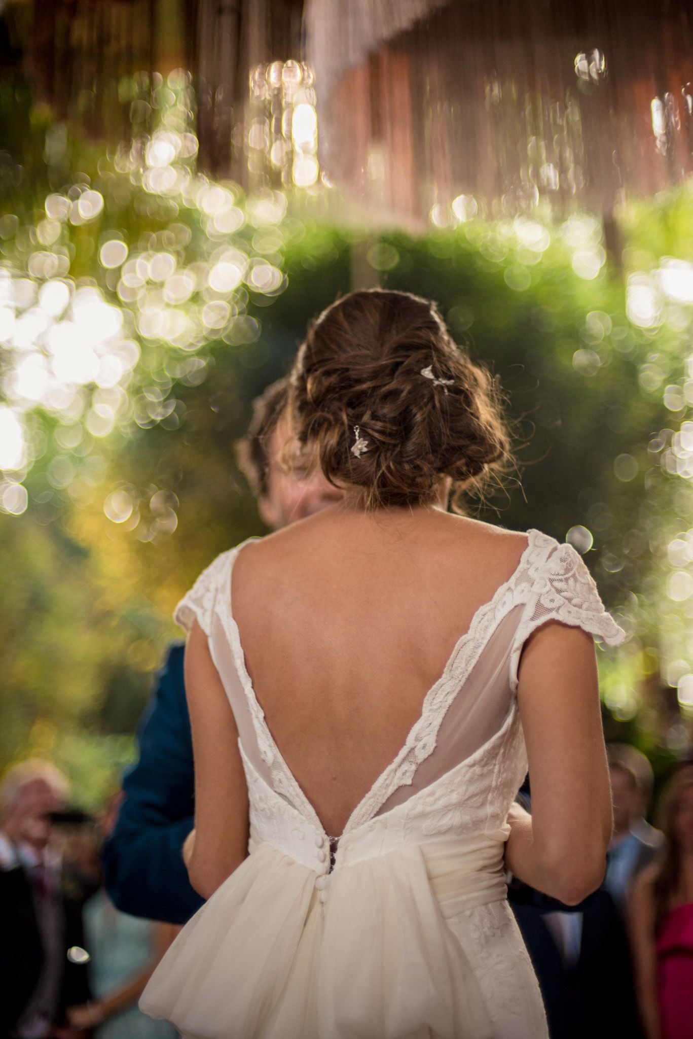 Back view of bride in lace dress with deep V design during reception.