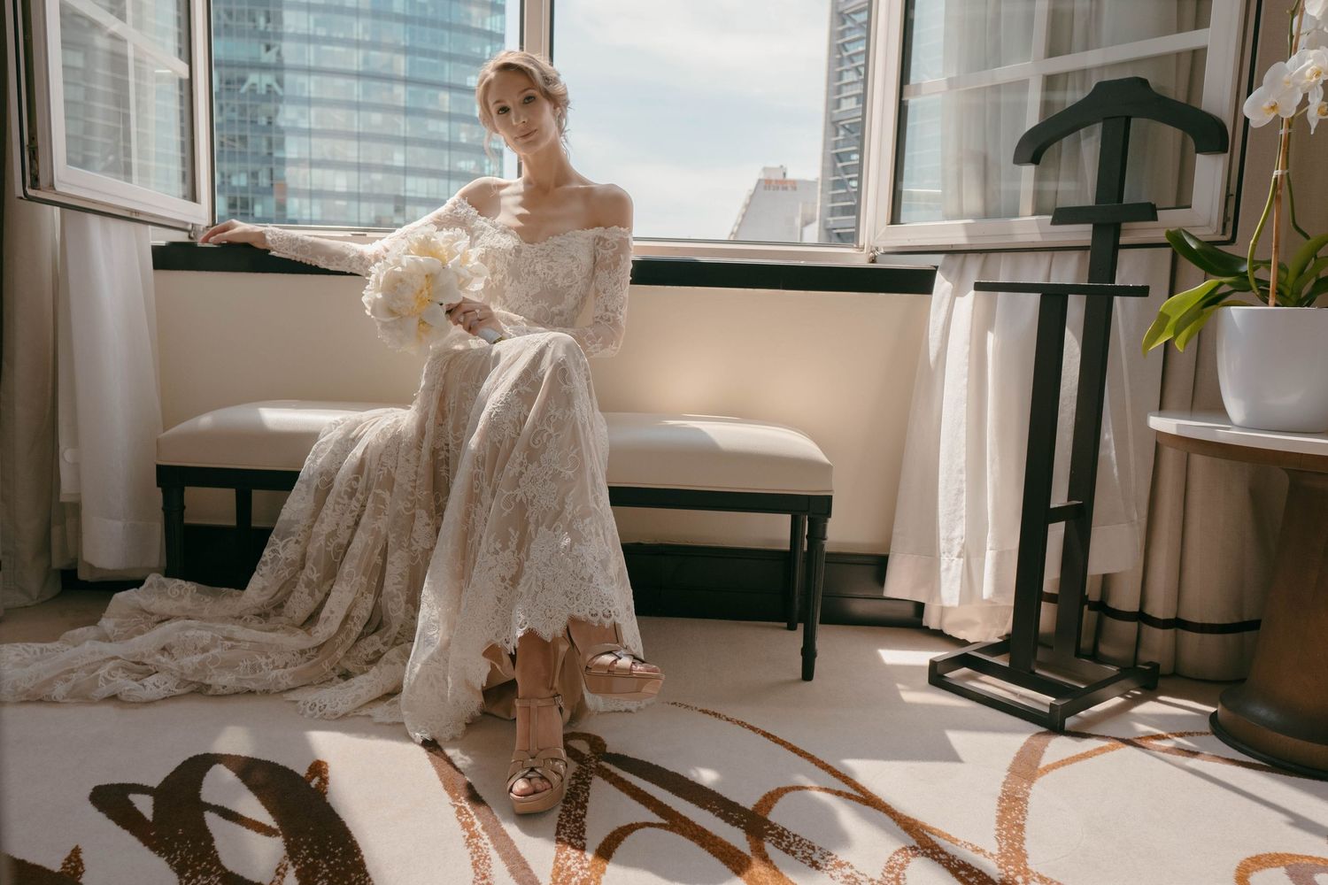 An elegant wedding dress displays intricate details against a modern city backdrop.