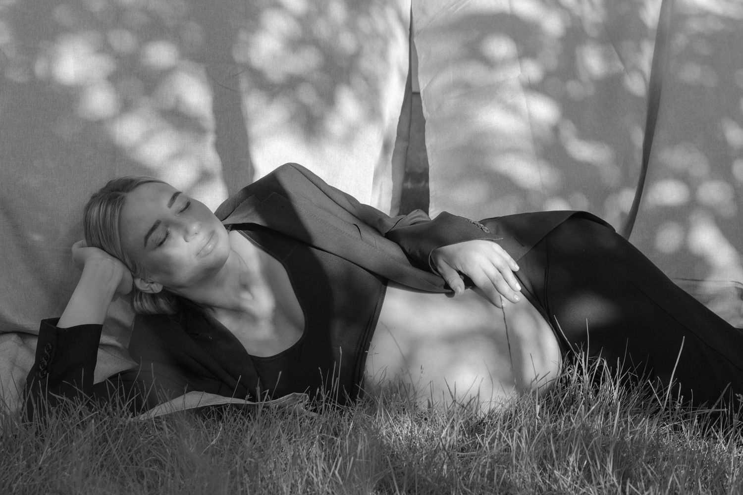 Artistic black and white portraits of someone laying in grass.