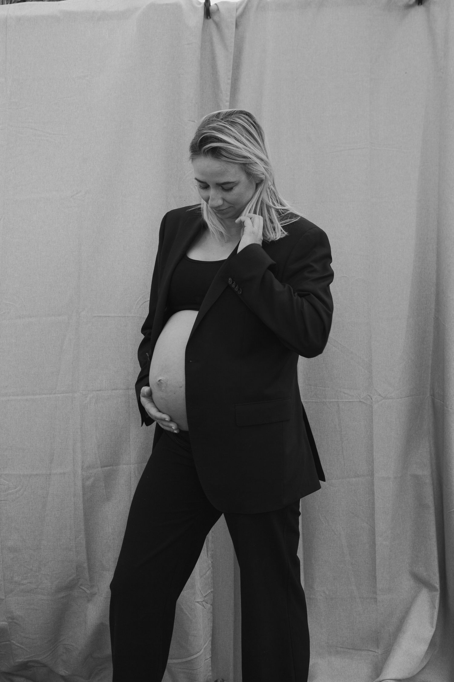 Artistic black and white maternity portrait against a white backdrop.