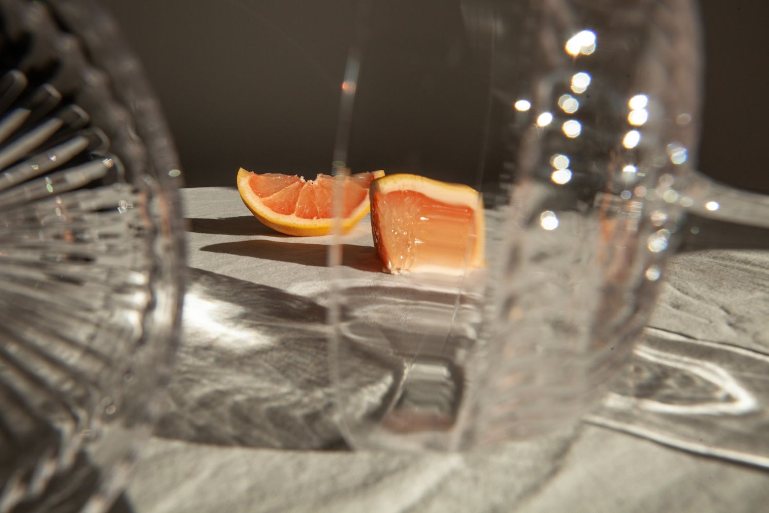 Orange citrus slices on a table with crystal glassware creating a soft bokeh effect in the background.