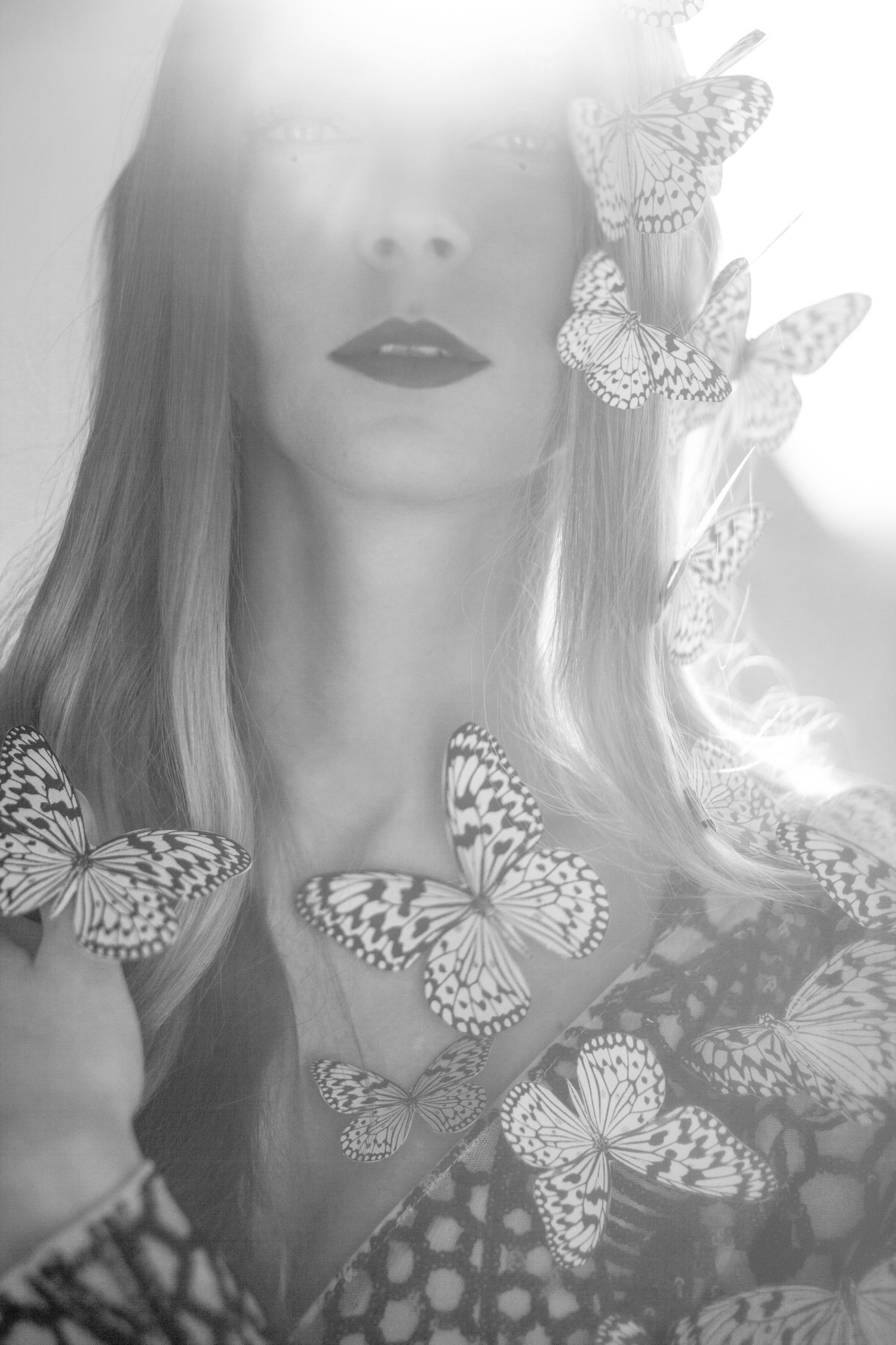 Black and white portrait adorned with white butterflies creating a soft, romantic atmosphere.