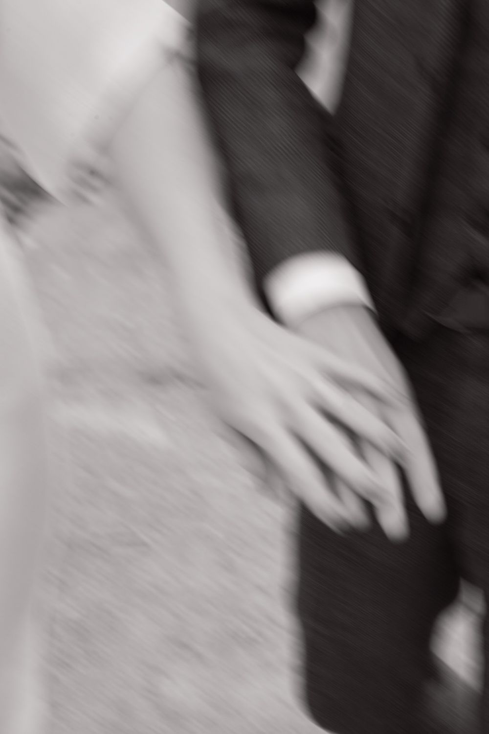 A blurred black and white motion photograph showing hands in movement against a dark background.