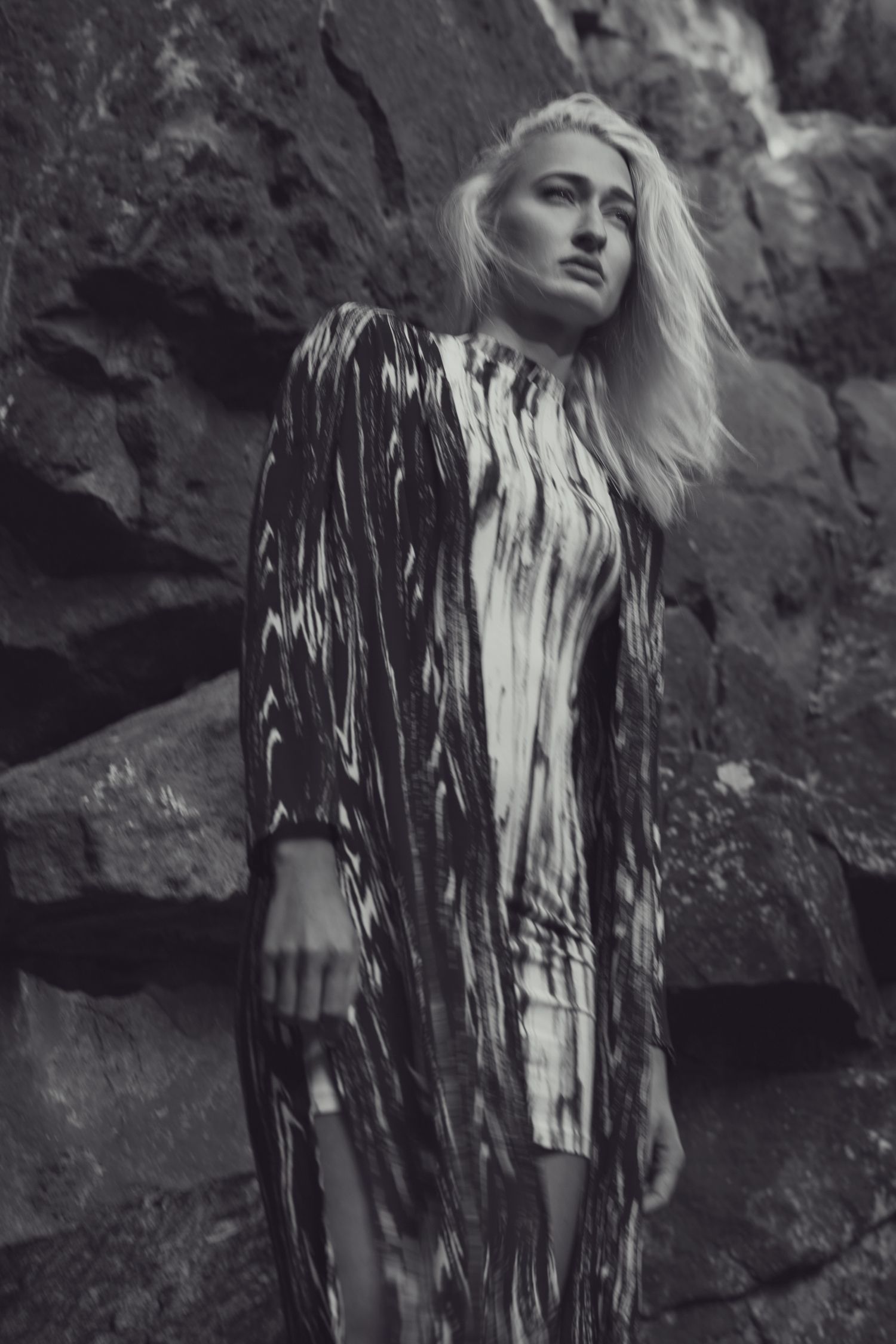 Fashion portrait showing a person in a striped dress against textured stone background.