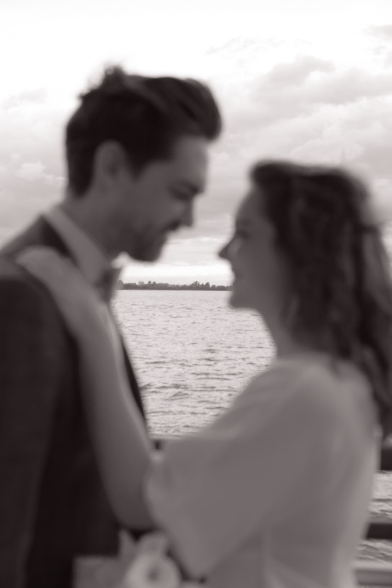 A romantic couple embraces at sunset by the ocean in a series of black and white photographs.