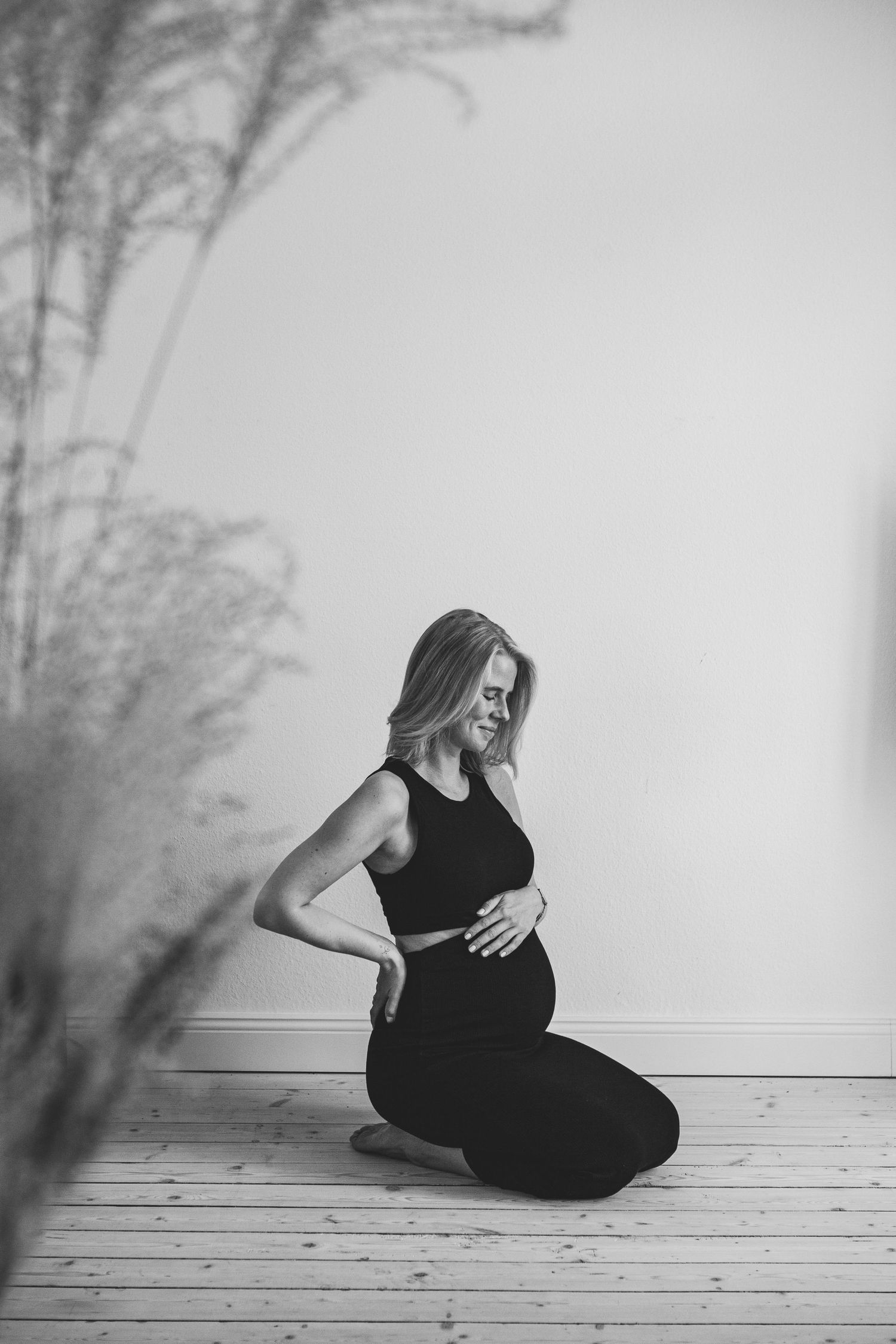 A series of black and white photos showing a person in a black dress sitting alone on a wooden floor.