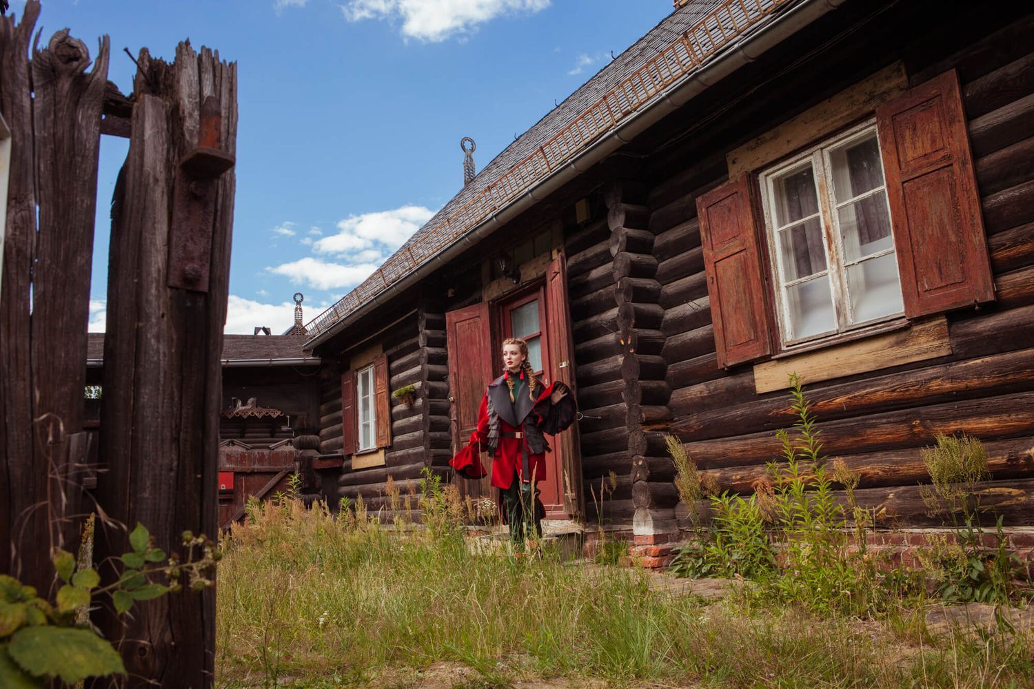 Fashion photo shoot set against traditional log cabin architecture with rustic wooden details.