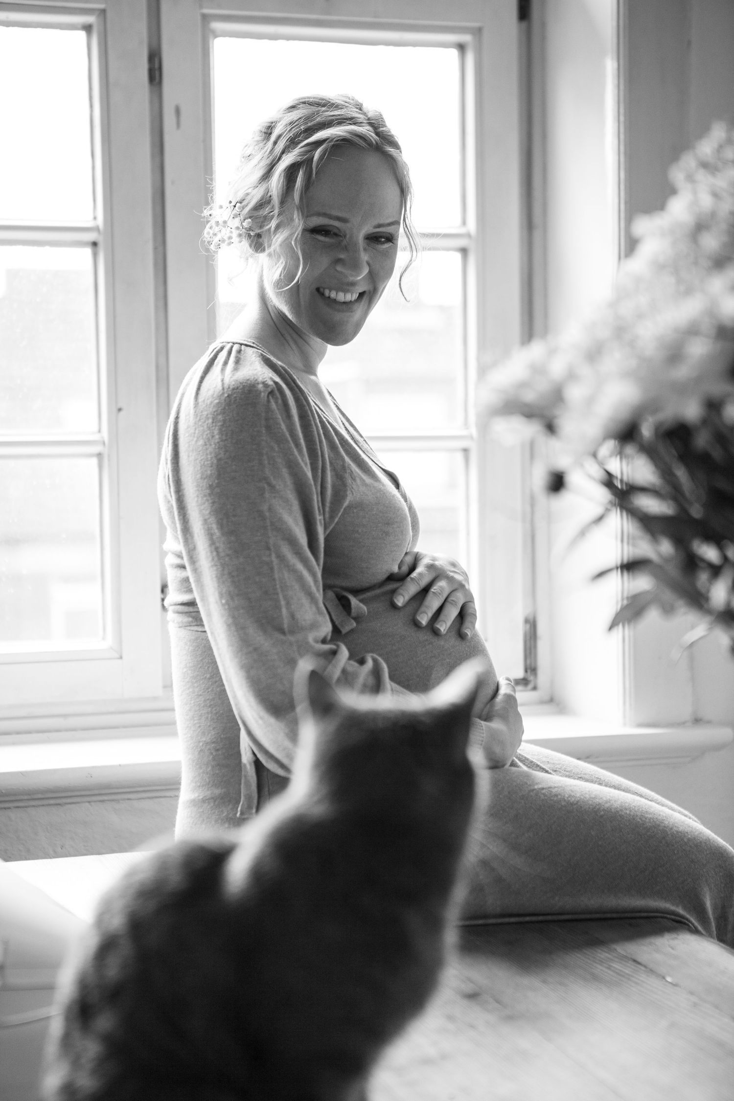 A heartwarming black and white photo strip showing playful interaction between a cat and person near a window.