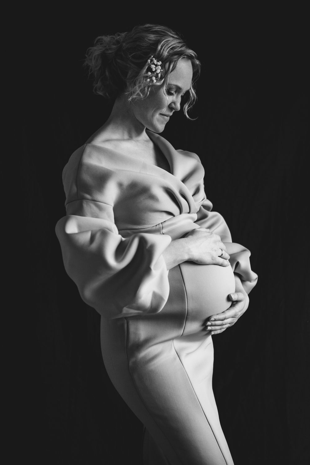 Artistic black and white maternity portrait showing an elegant off-shoulder dress.