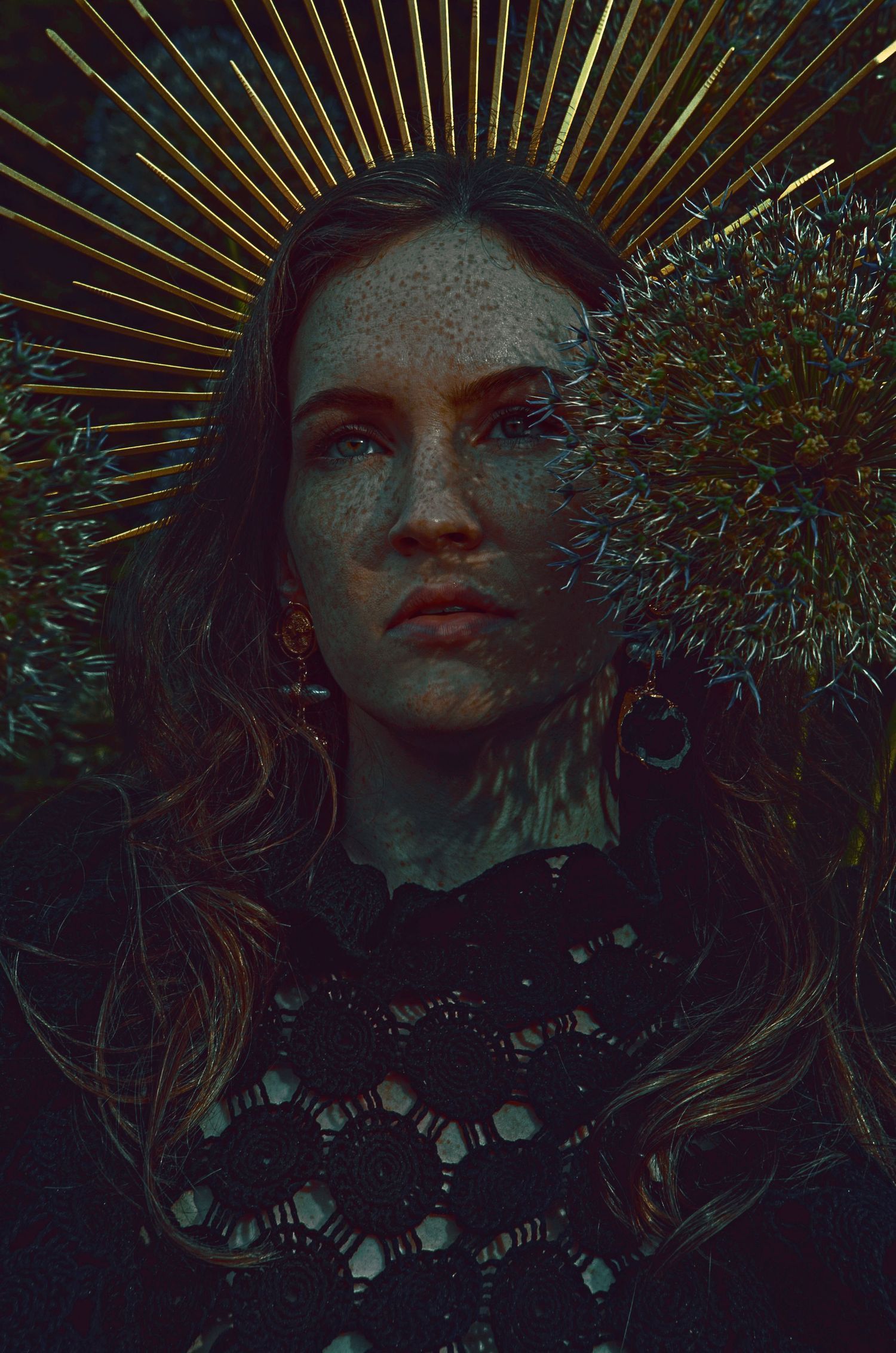 Artistic portrait with a golden sunburst crown effect featuring freckles and dramatic dark lighting.