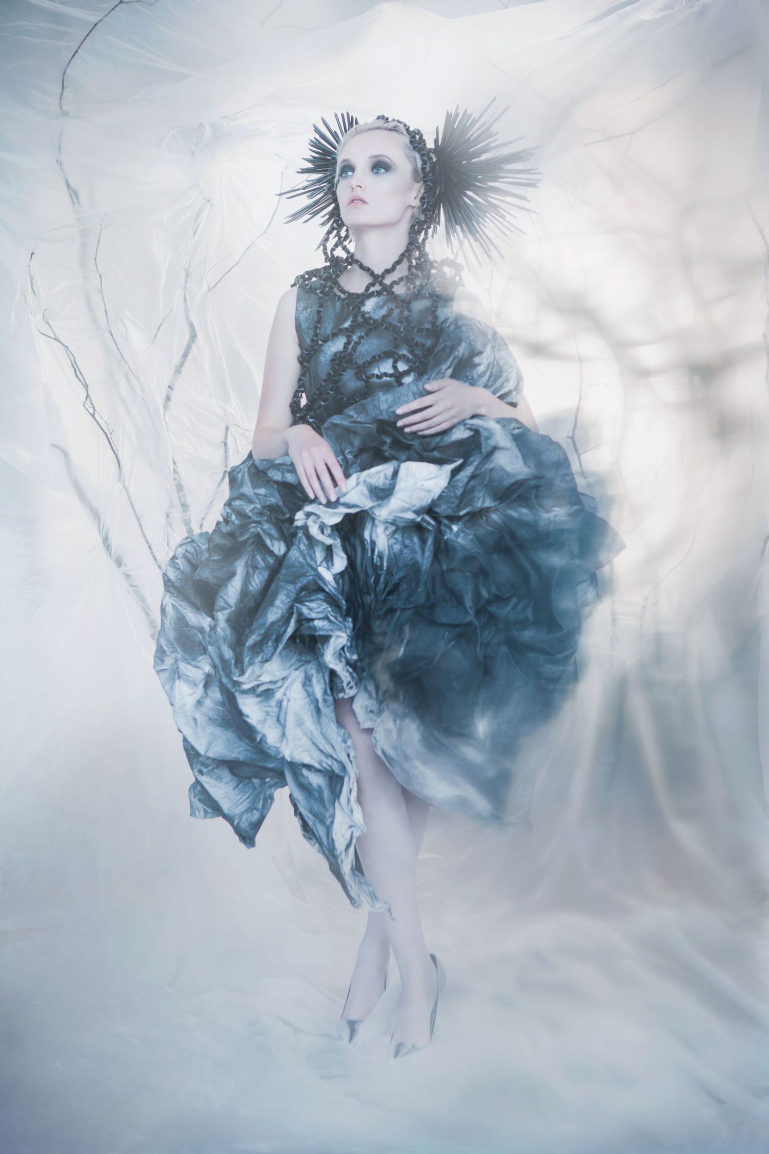 Ethereal fashion photograph showing a floating figure in a billowing blue dress against a misty white backdrop.