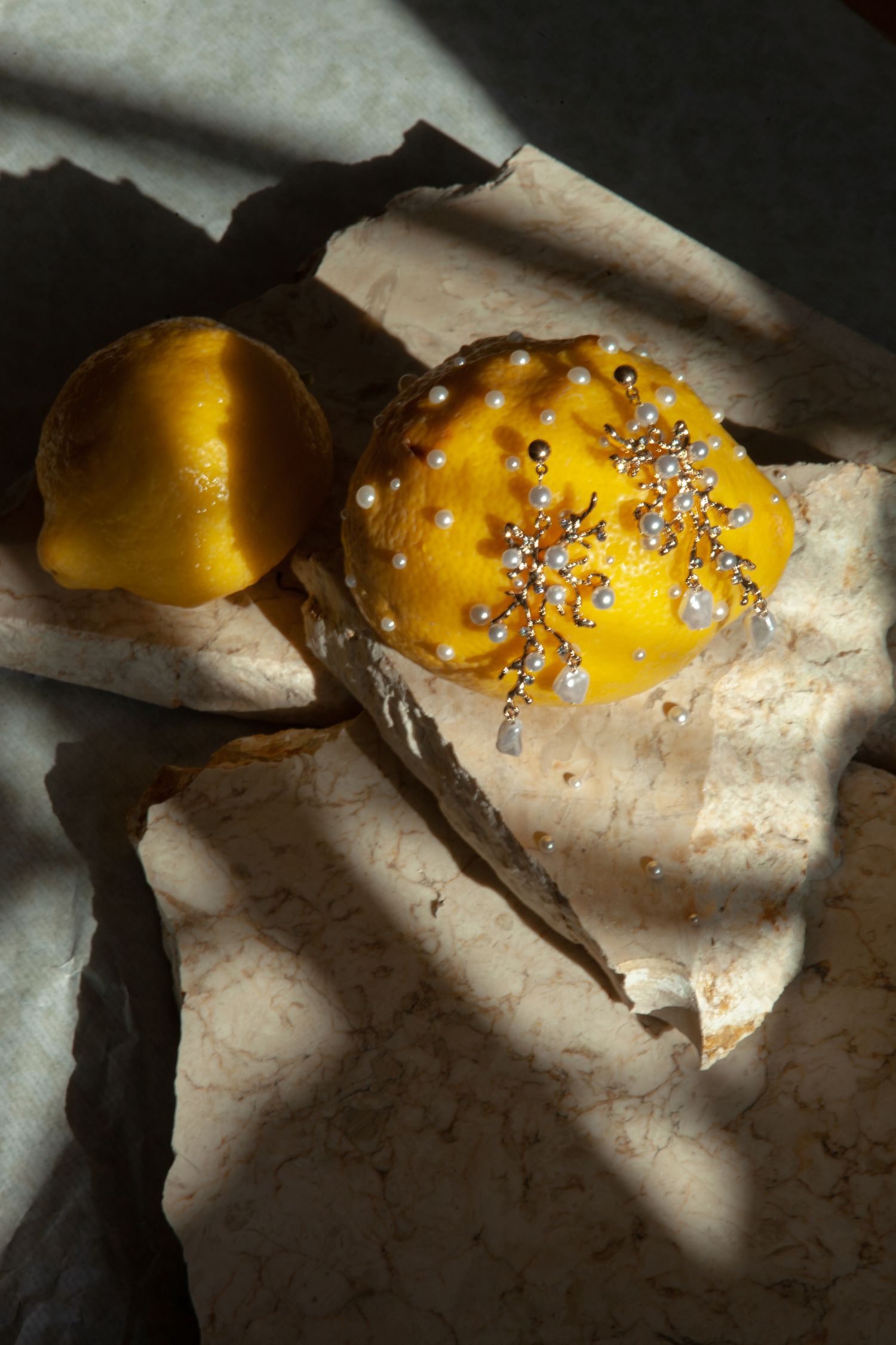 Close-up of decorative yellow citrus with silver sprinkles on white paper.