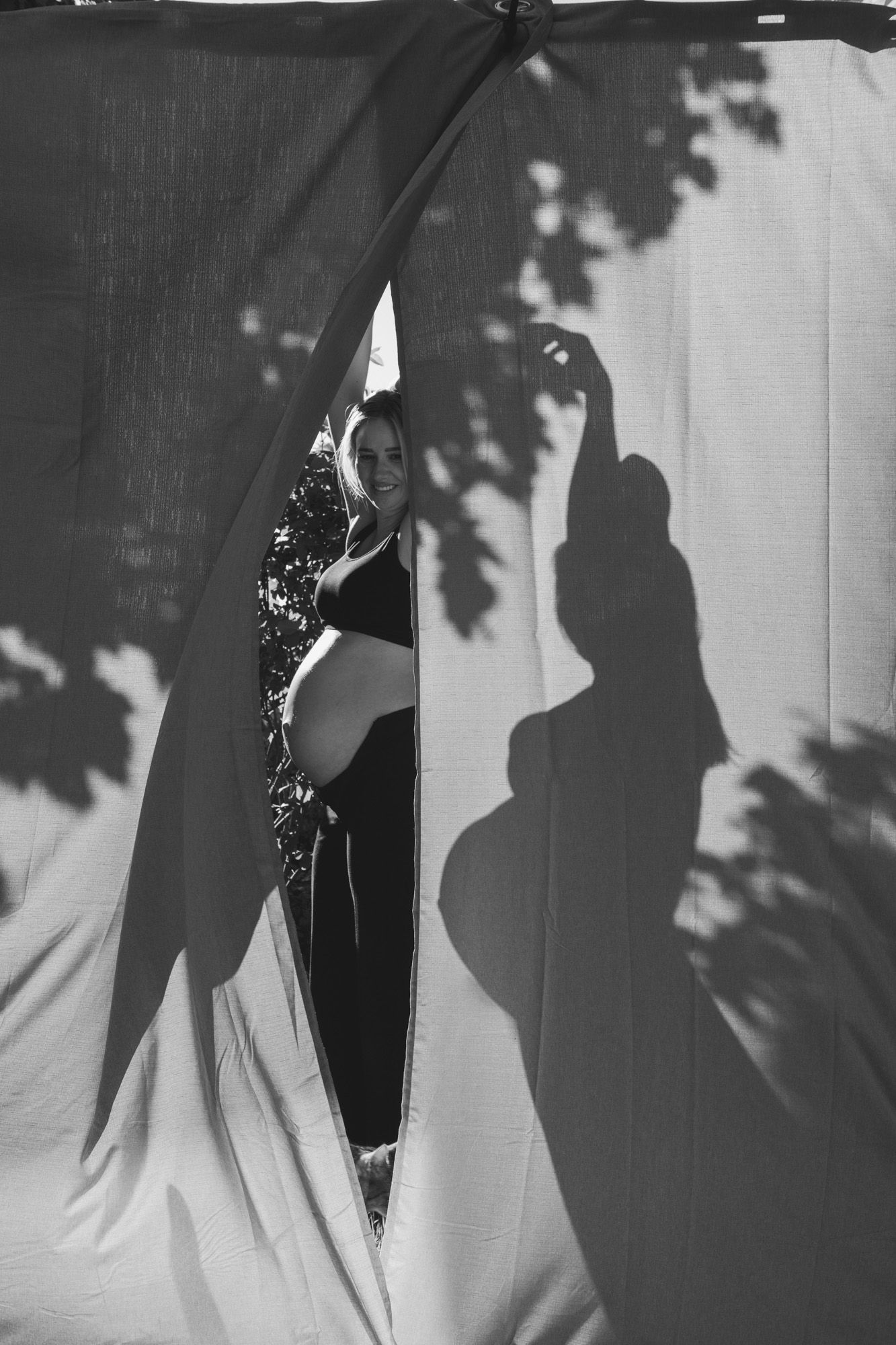 Artistic black and white silhouette photograph with shadows cast through fabric in an outdoor setting.
