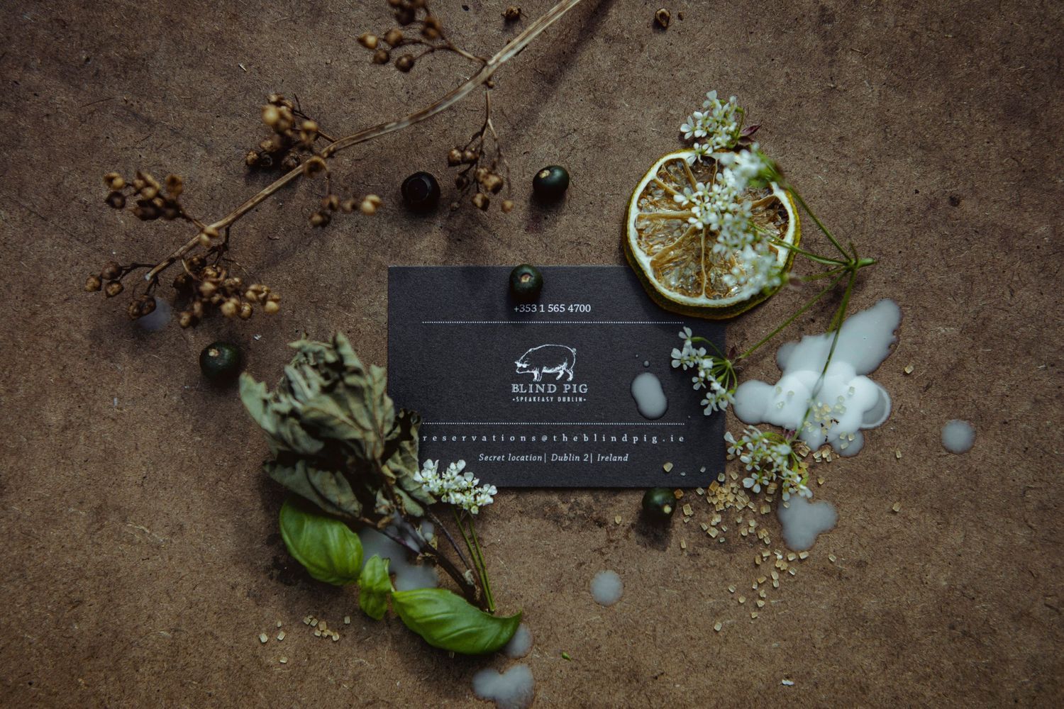 Flat lay of dried flowers and botanical elements around a black business card.