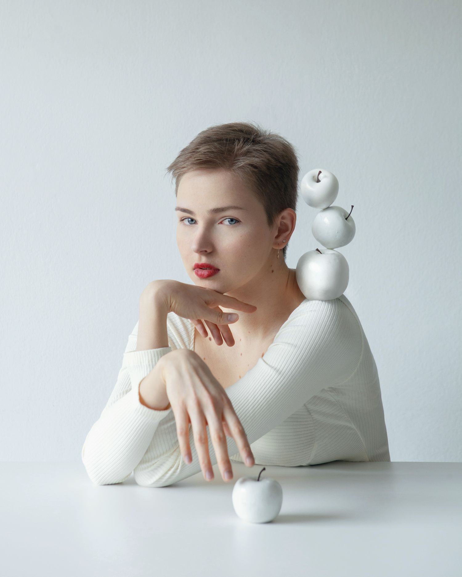 Artistic fashion photo series with white spheres and minimalist styling against light background.