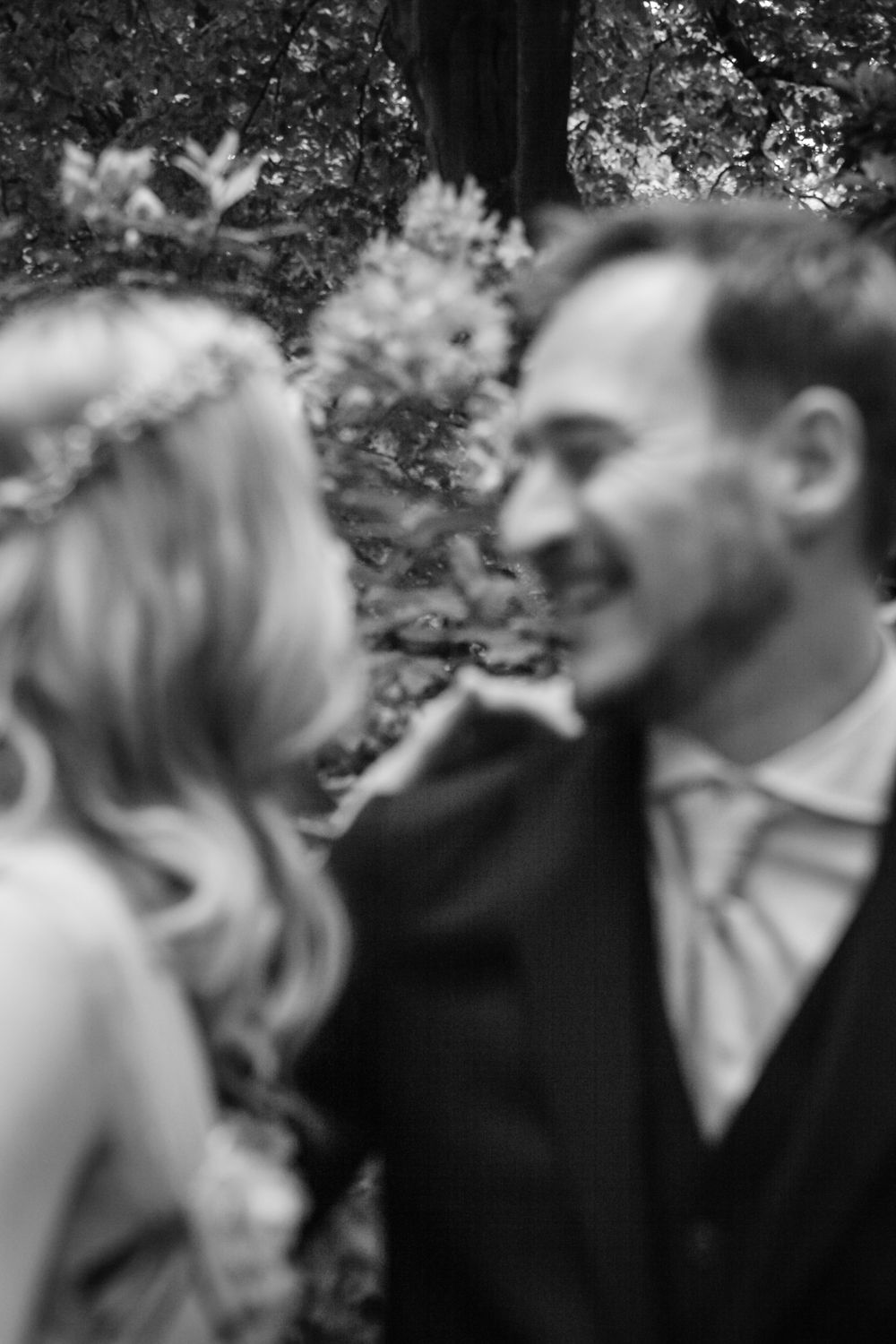 Black and white romantic wedding photograph of a couple sharing a tender moment in soft focus with flowers in background.