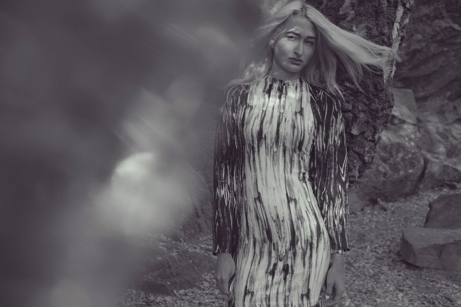Ethereal black and white portrait of a person wearing a white dress with dripping paint effect against a blurred background.