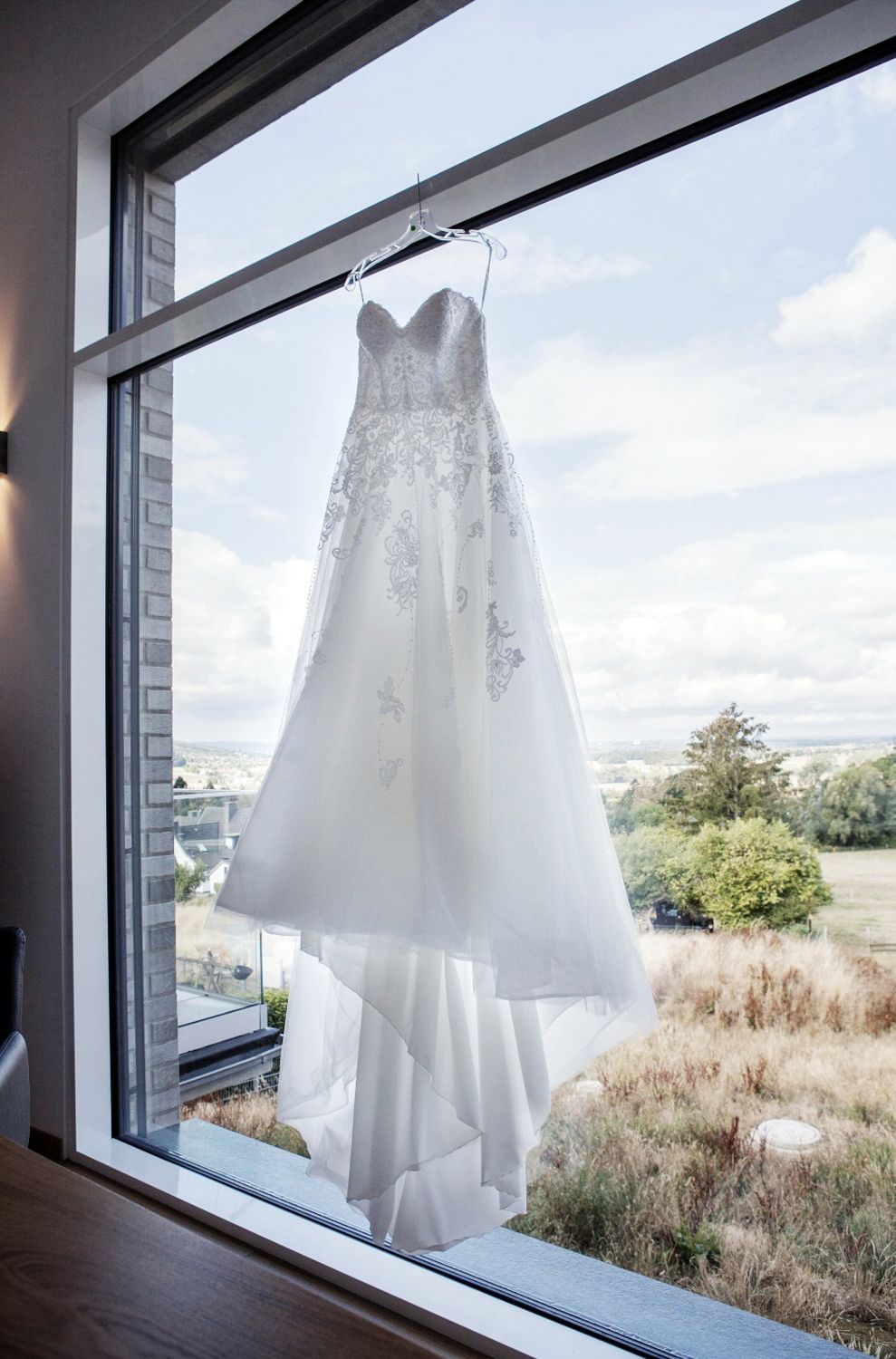 A white wedding dress hangs by a window overlooking grass and trees across multiple photo frames.