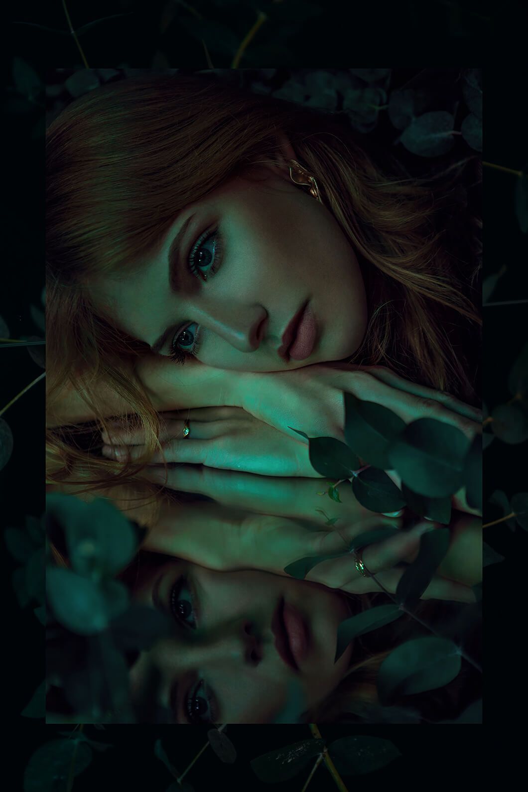 Dramatic portrait with green lighting and mirror reflection creating mystical atmosphere.