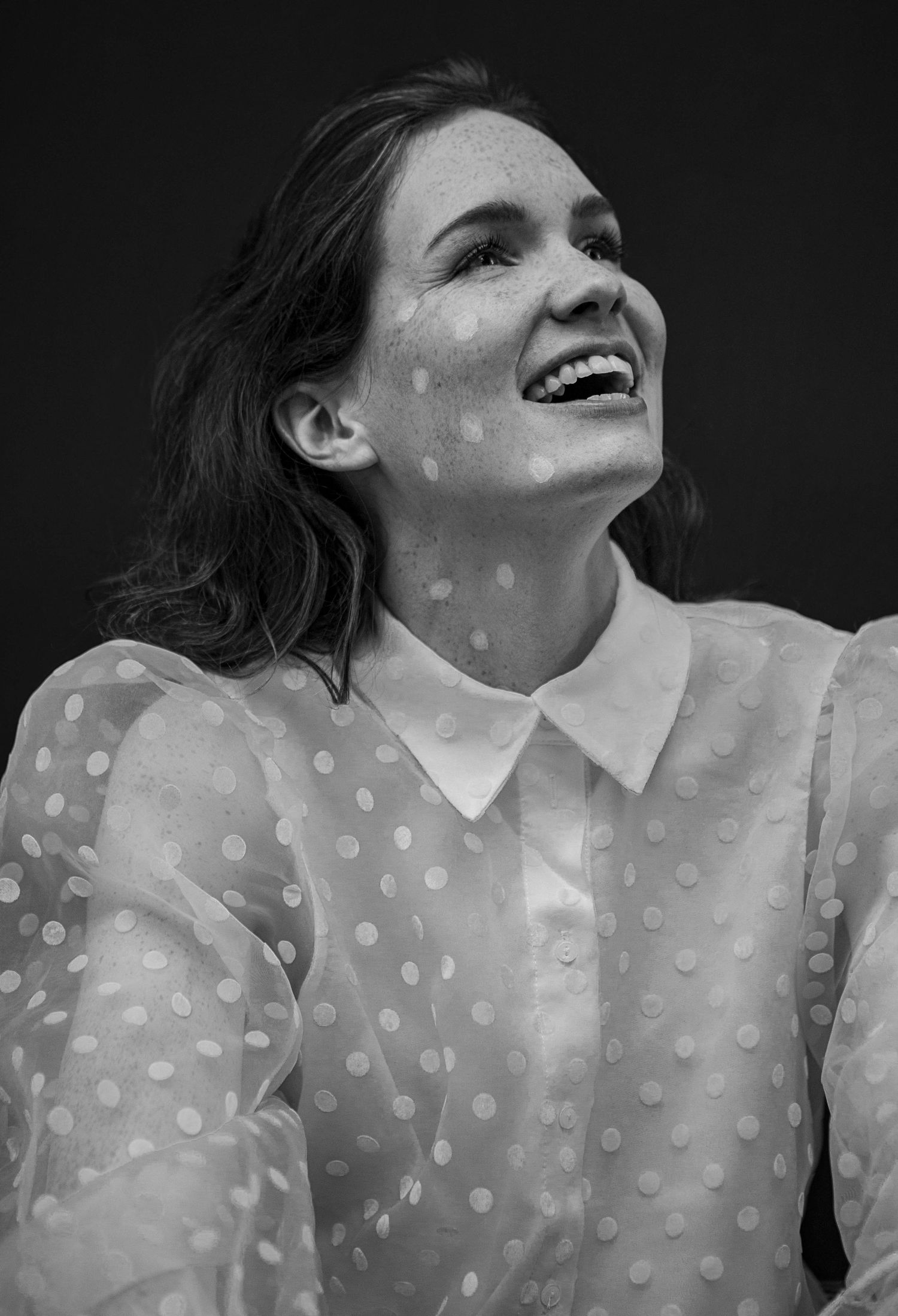 Black and white portrait in polka dot sheer blouse showing joyful expression.