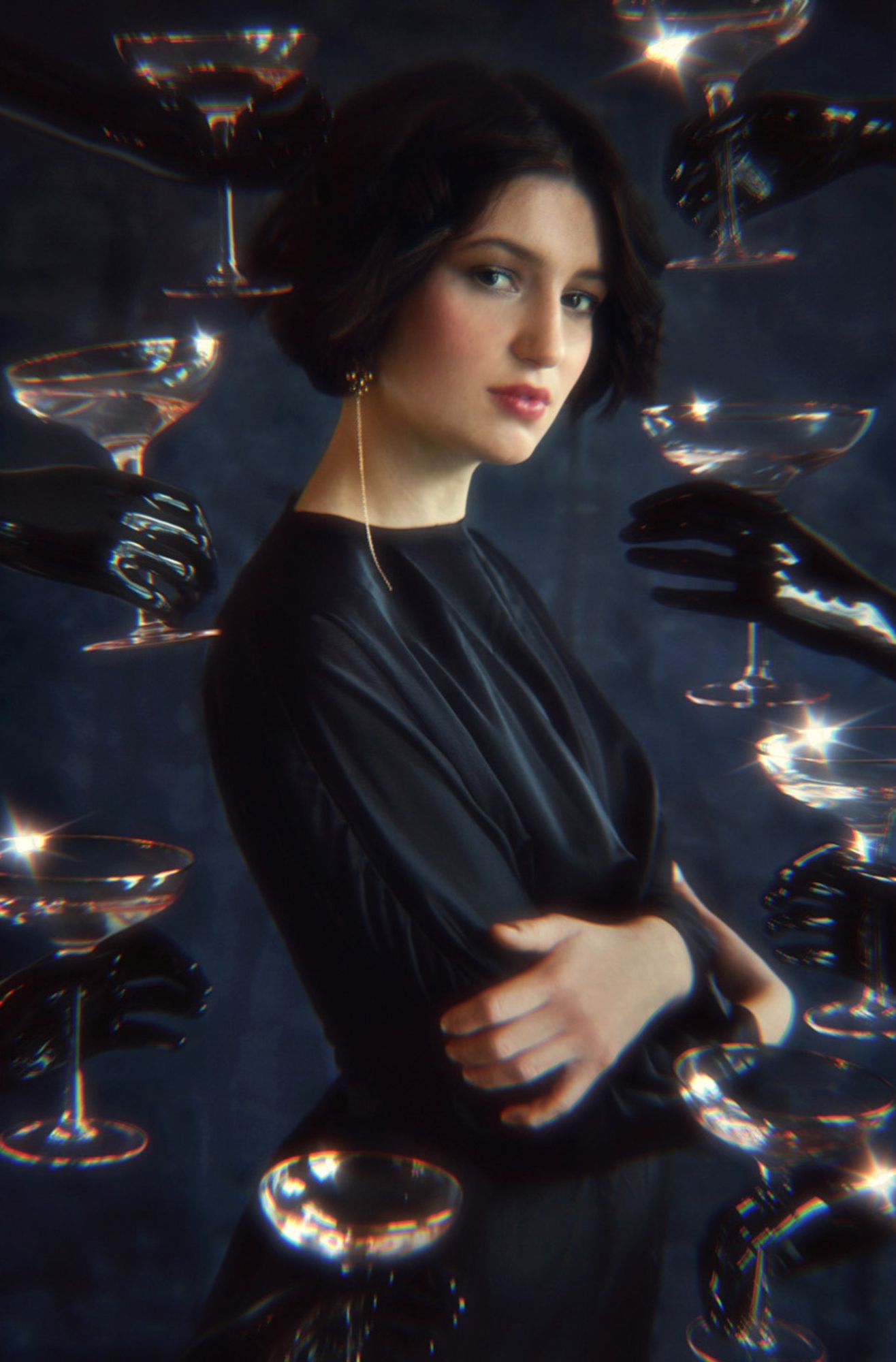 Artistic portrait surrounded by floating champagne glasses in dark setting.