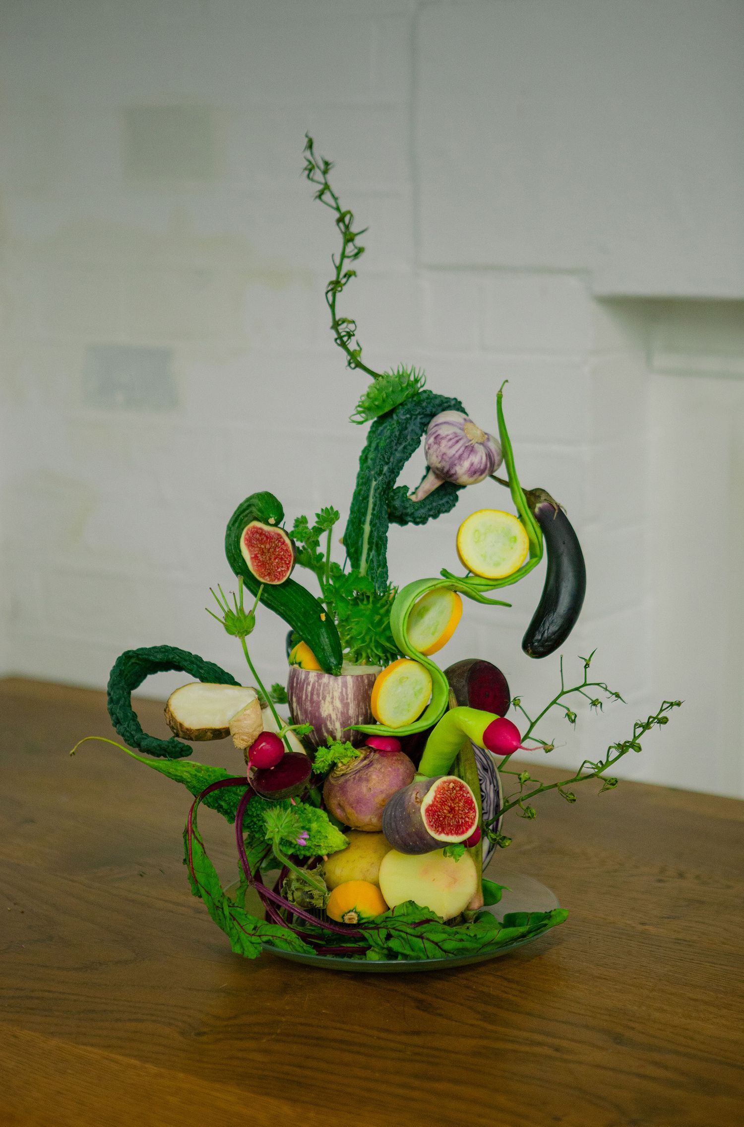 Creative fruit and vegetable arrangement featuring sliced citrus and green foliage in a sculptural design.