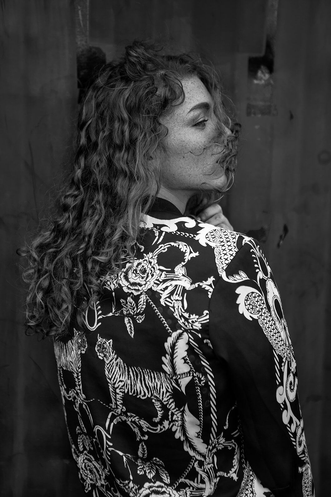 Dramatic black and white portrait showcasing an ornate patterned jacket with animal motifs.