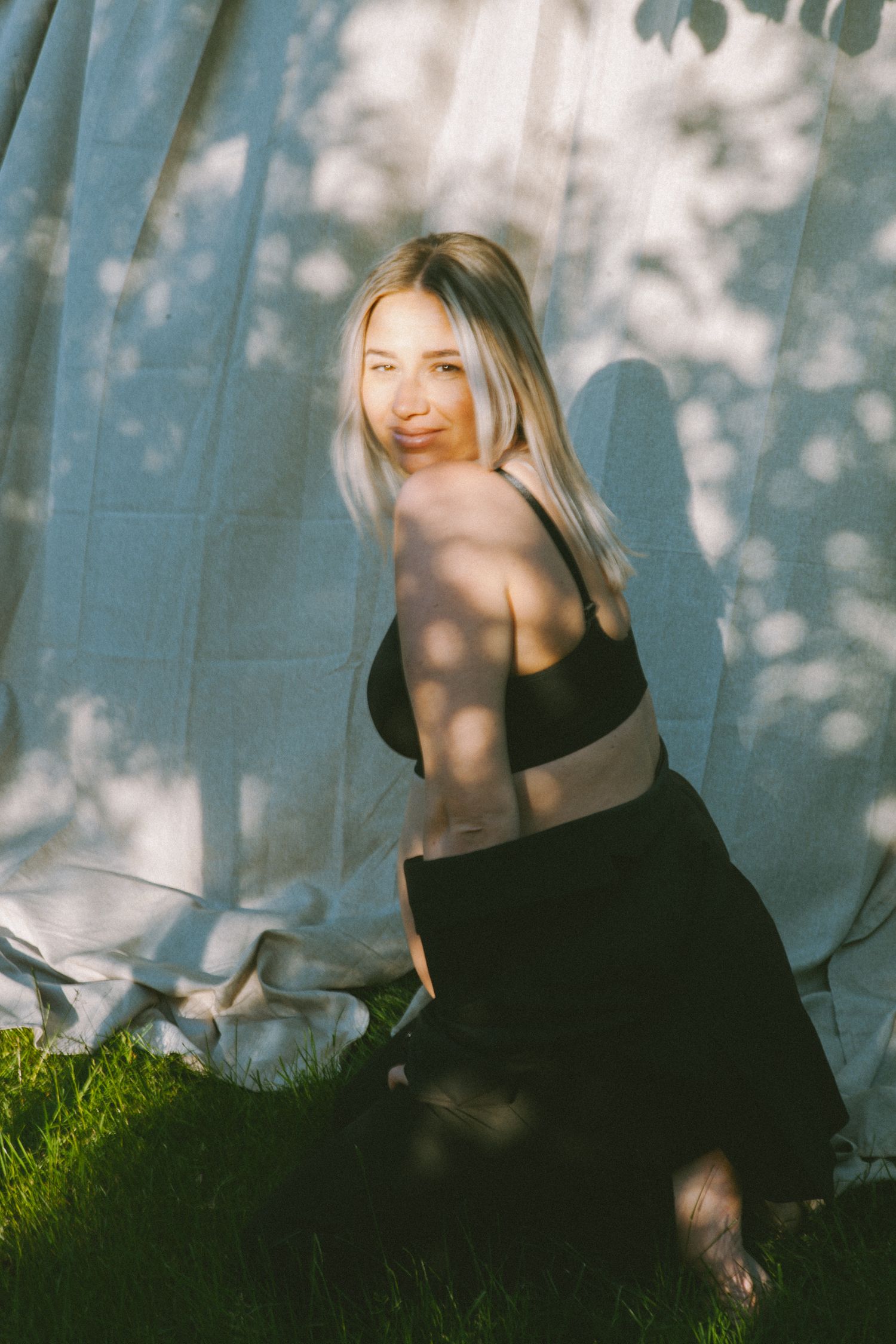 Artistic outdoor photoshoot with soft light filtering through trees creating ethereal shadows.