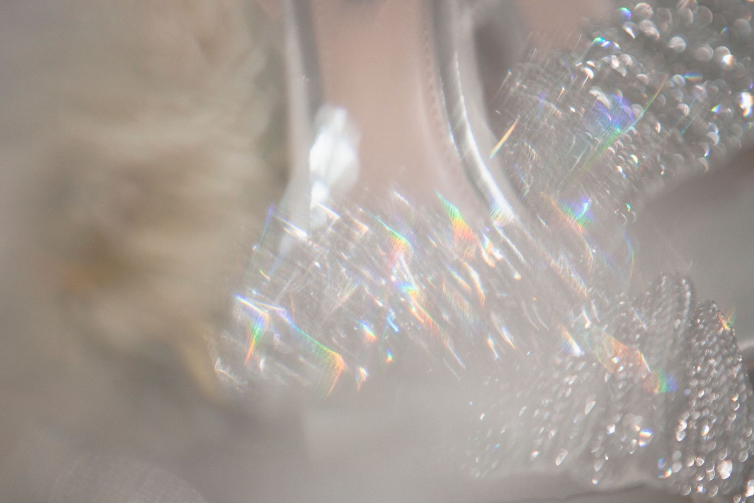 Close-up macro shot of sparkling crystal or glass with rainbow light reflections.