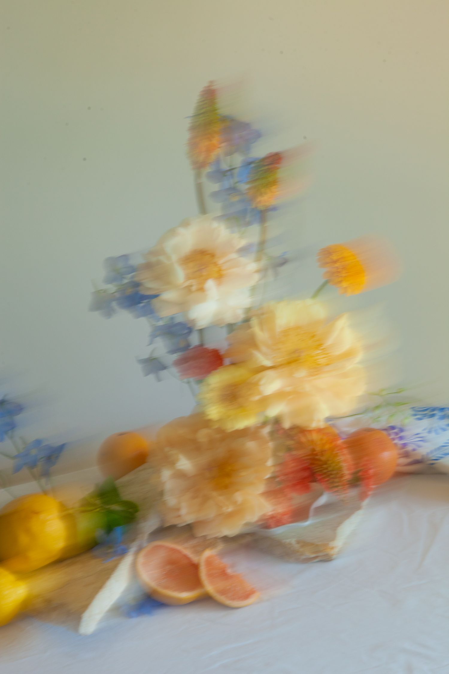 Abstract motion blur photograph of flowers and citrus fruits in soft pastel colors.