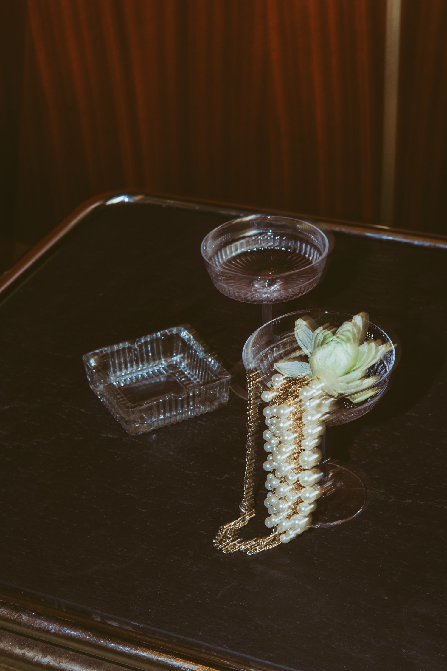 Still life of cocktail glass, ashtray and decorative accessories on dark table.