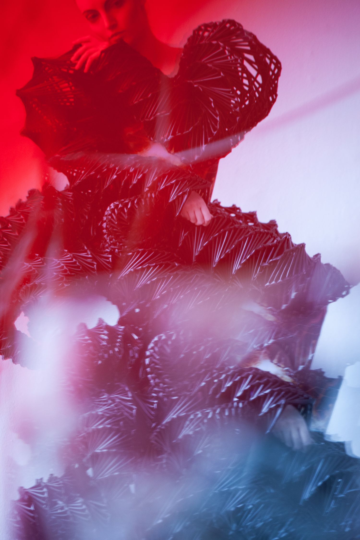 Textured abstract portrait in red and blue tones with crystalline patterns.