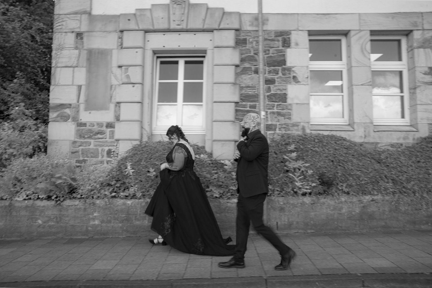 A series of black and white photos showing silhouetted figures walking past stone buildings and architectural structures.
