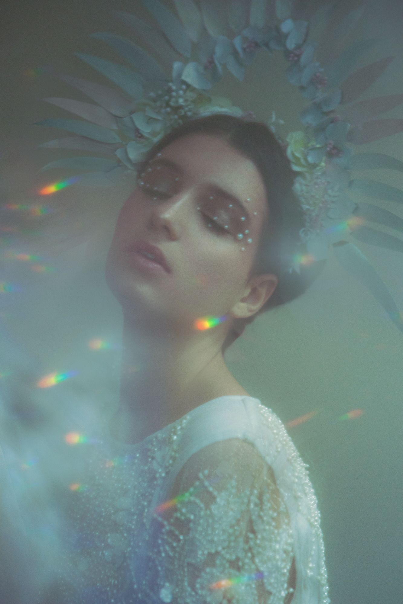 Ethereal portrait with crystal crown and sparkles in dreamy lighting.