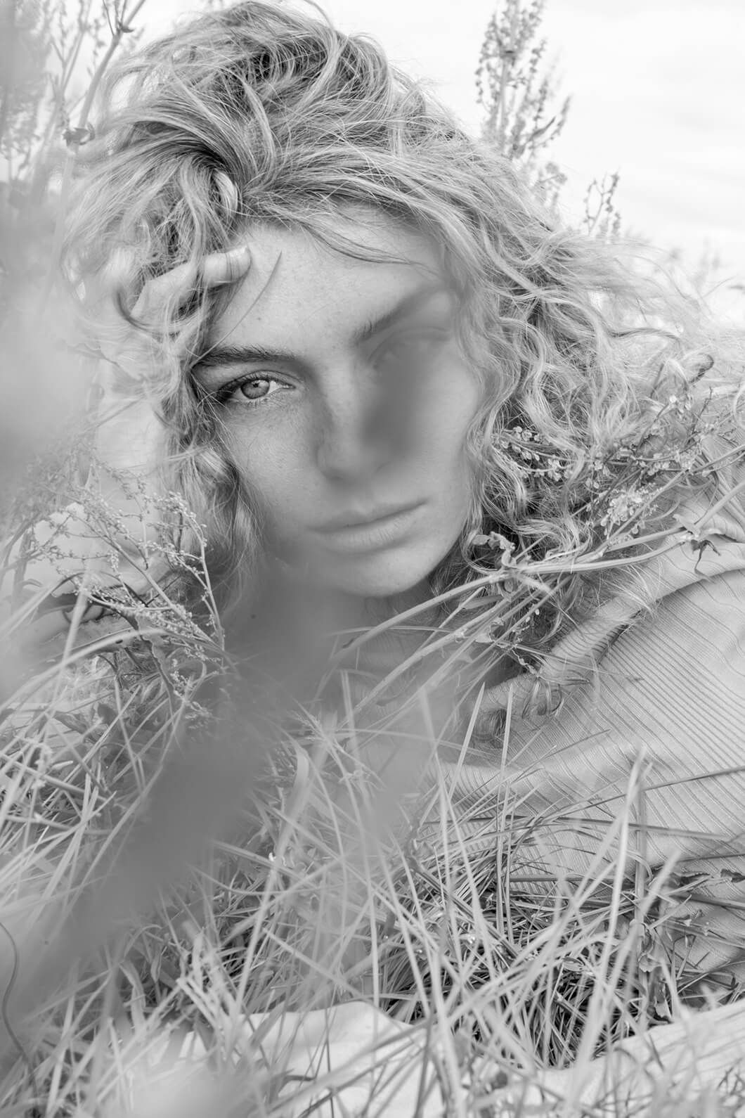 Artistic black and white portrait with hay or straw creating textural elements.