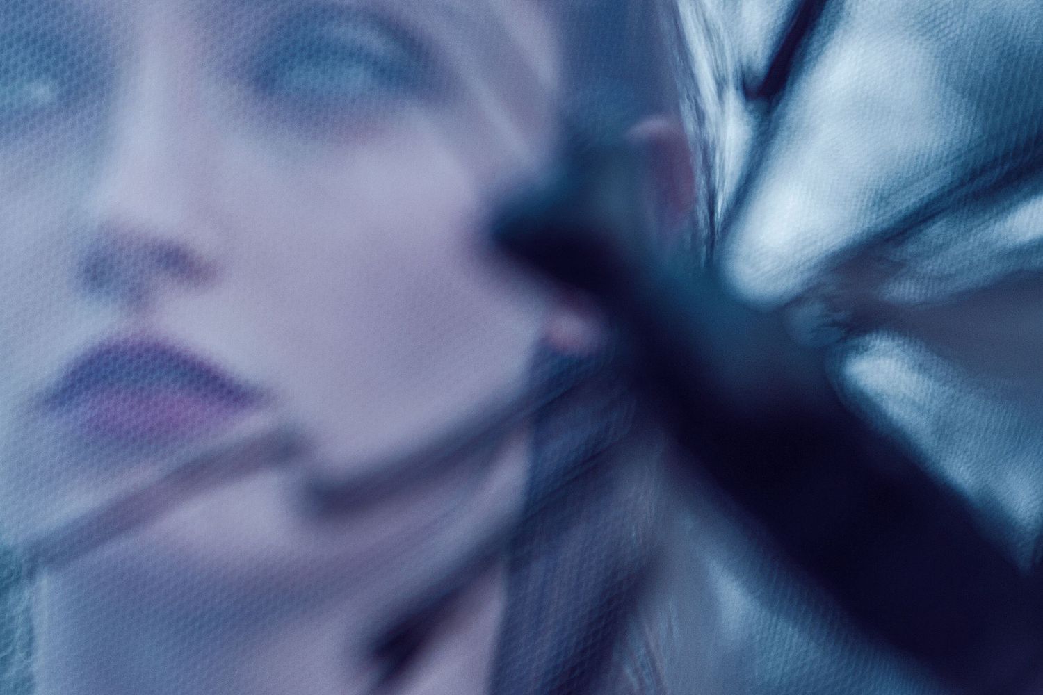 Blurred artistic portrait with ethereal blue tones creating a dreamy atmospheric effect.