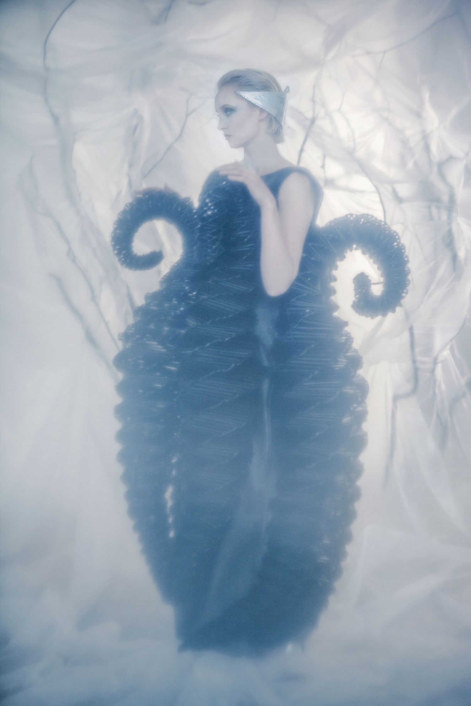 Artistic fashion photo features a dress with dramatic spiral designs against a dreamy white background.