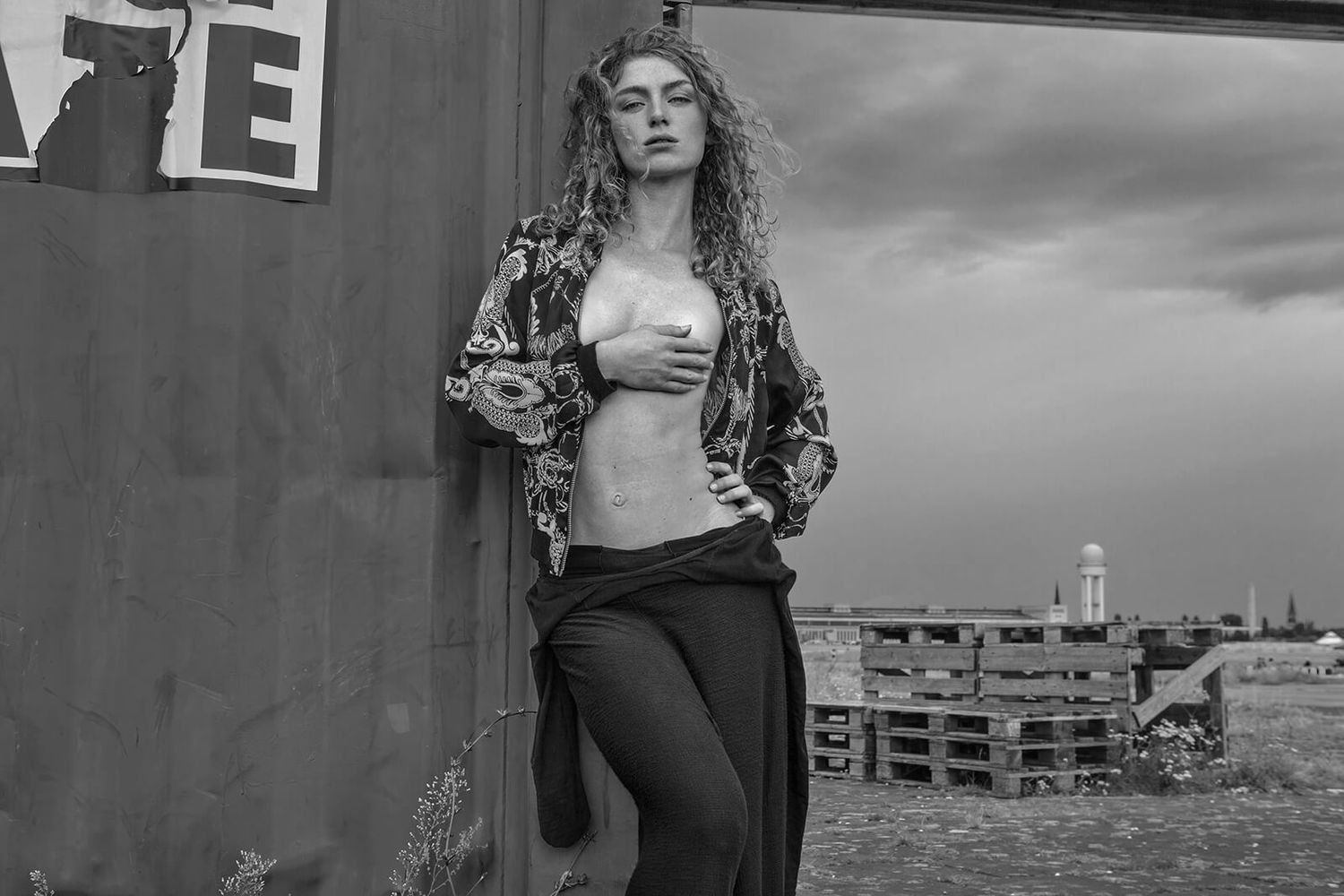 Black and white fashion photo showing an urban street style look with crop top and printed jacket.