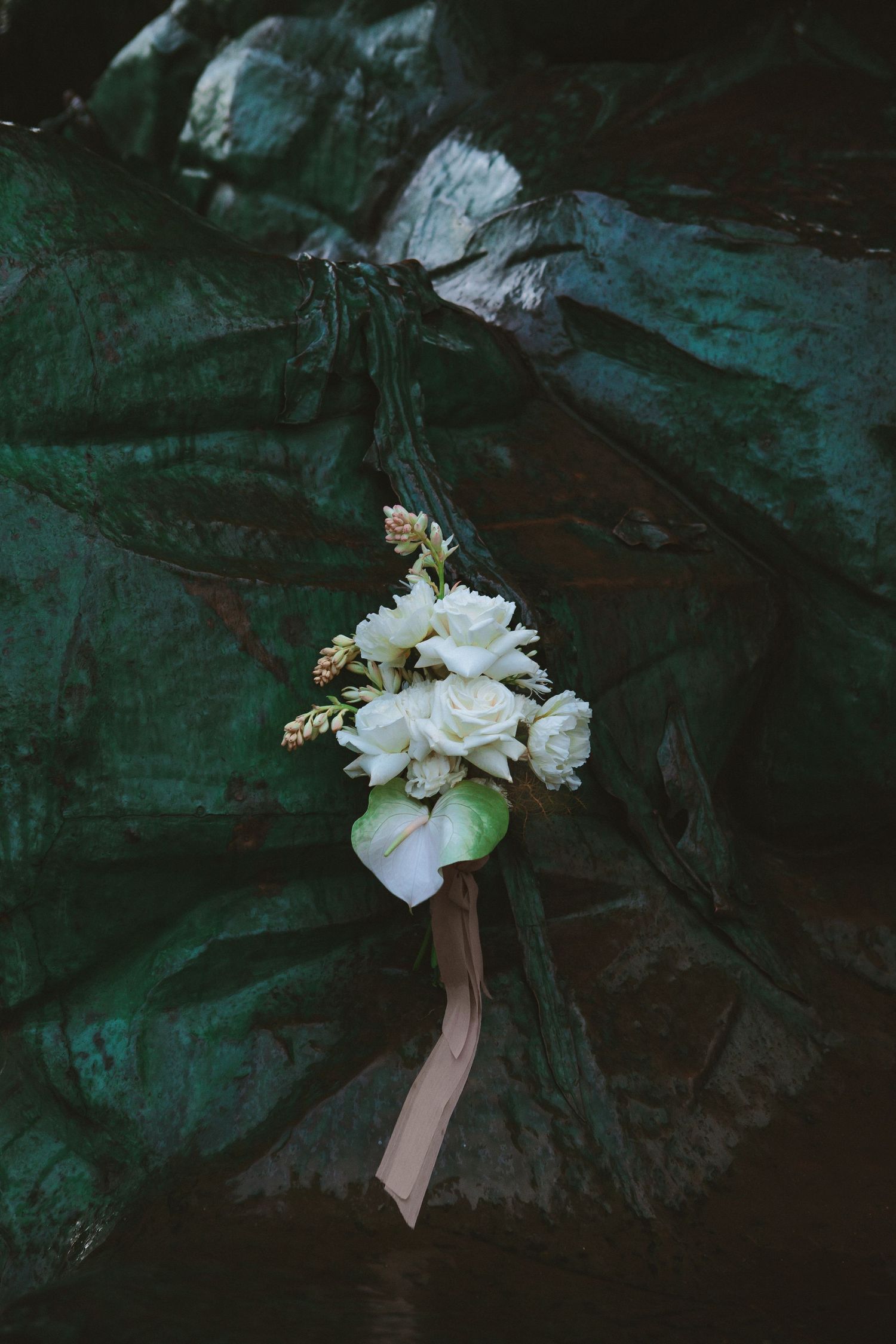 Delicate white floral bouquet arrangement against dark textured background.