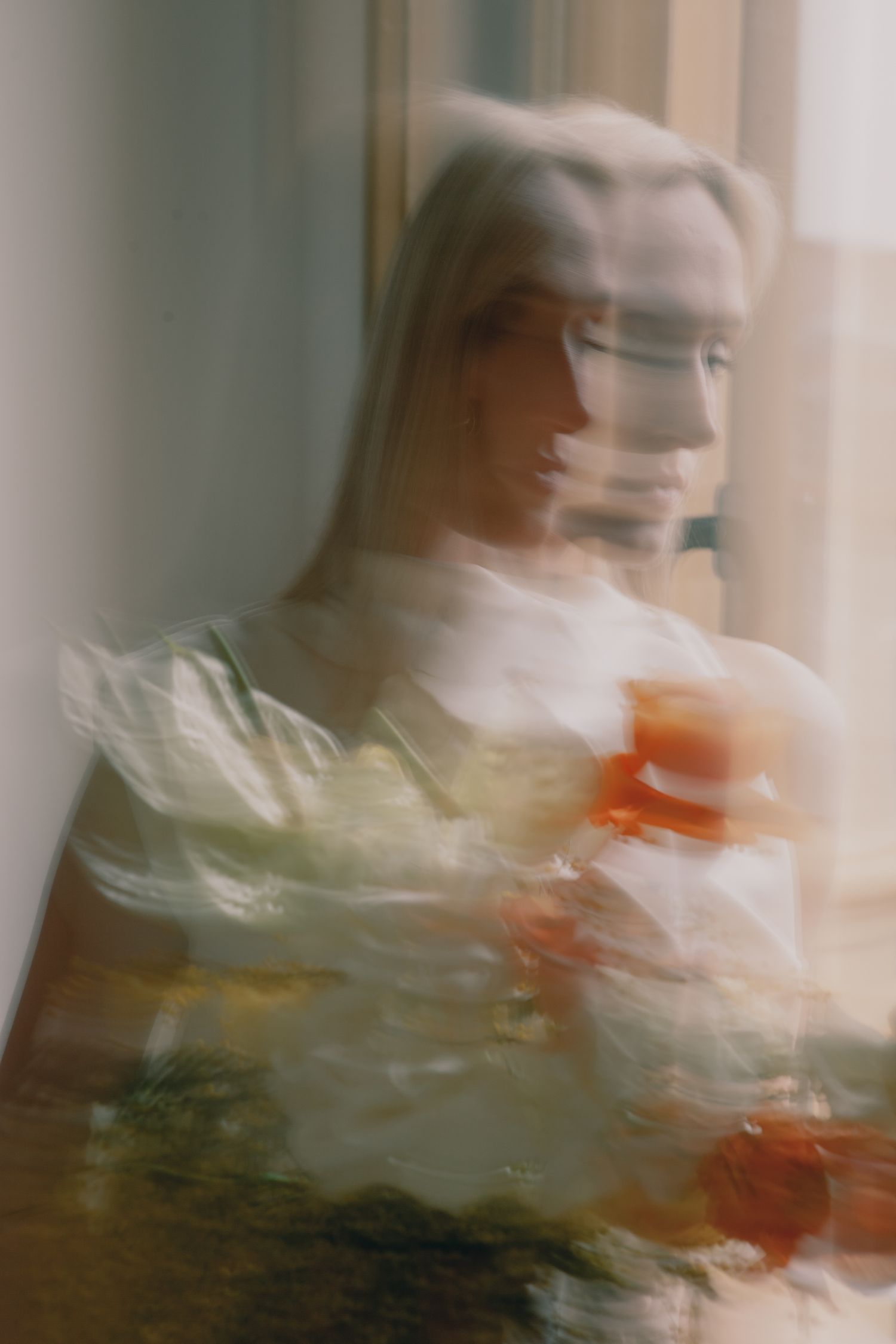 Artistic motion blur portrait with soft orange tones and natural window light.