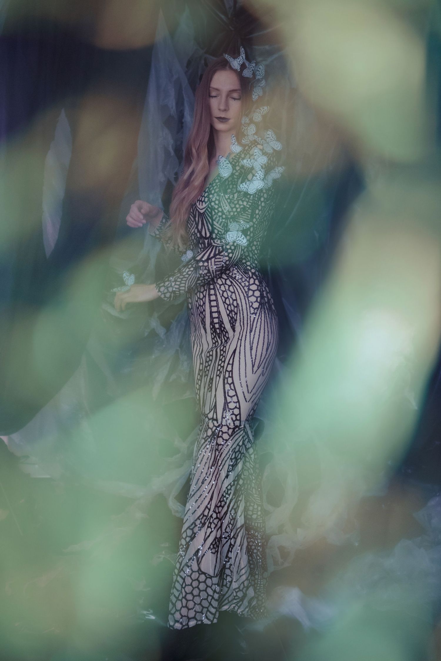 Ethereal fashion photo with patterned dress captured through blurred foliage.