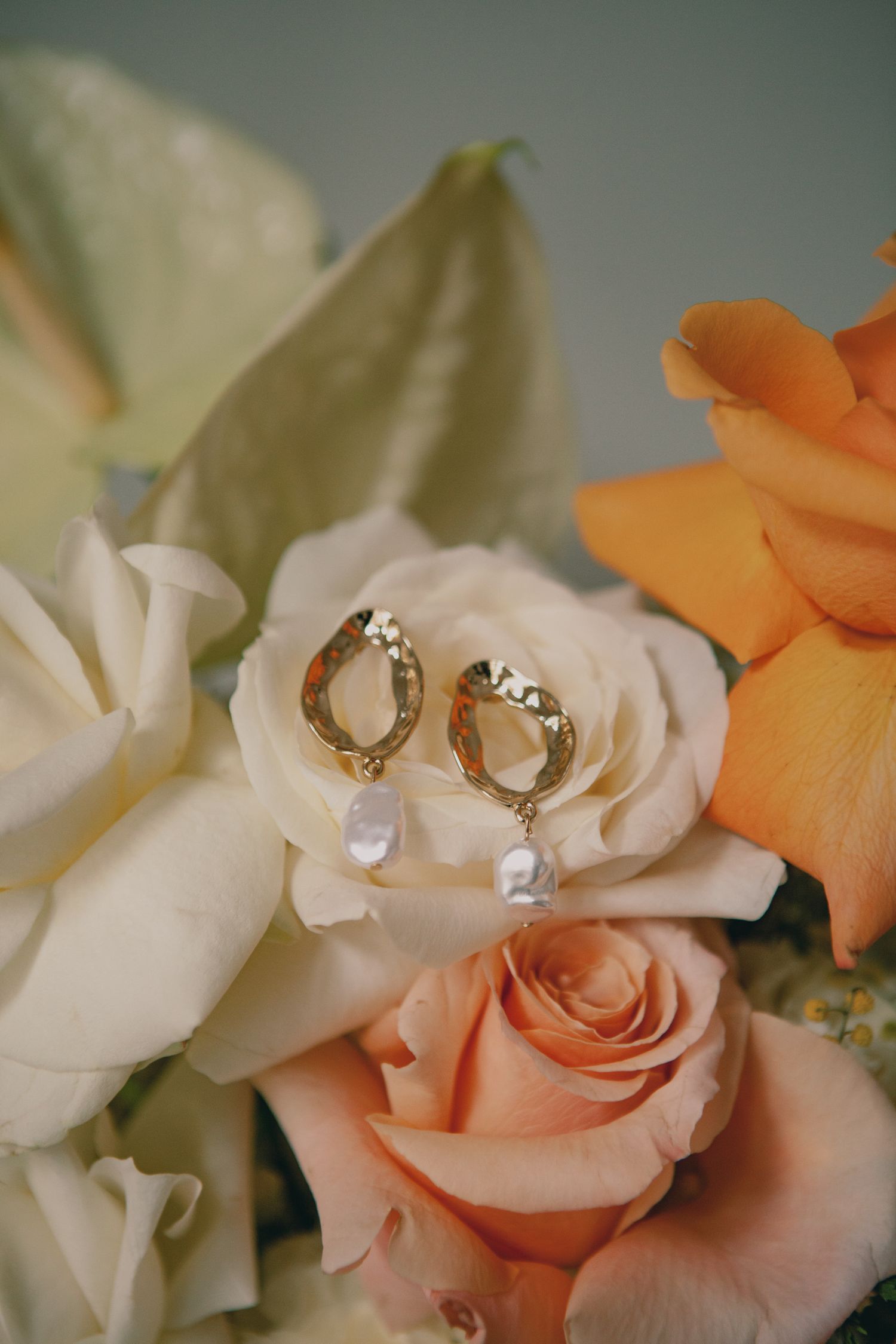 Wedding rings nestled on white and peach roses in bridal bouquet.