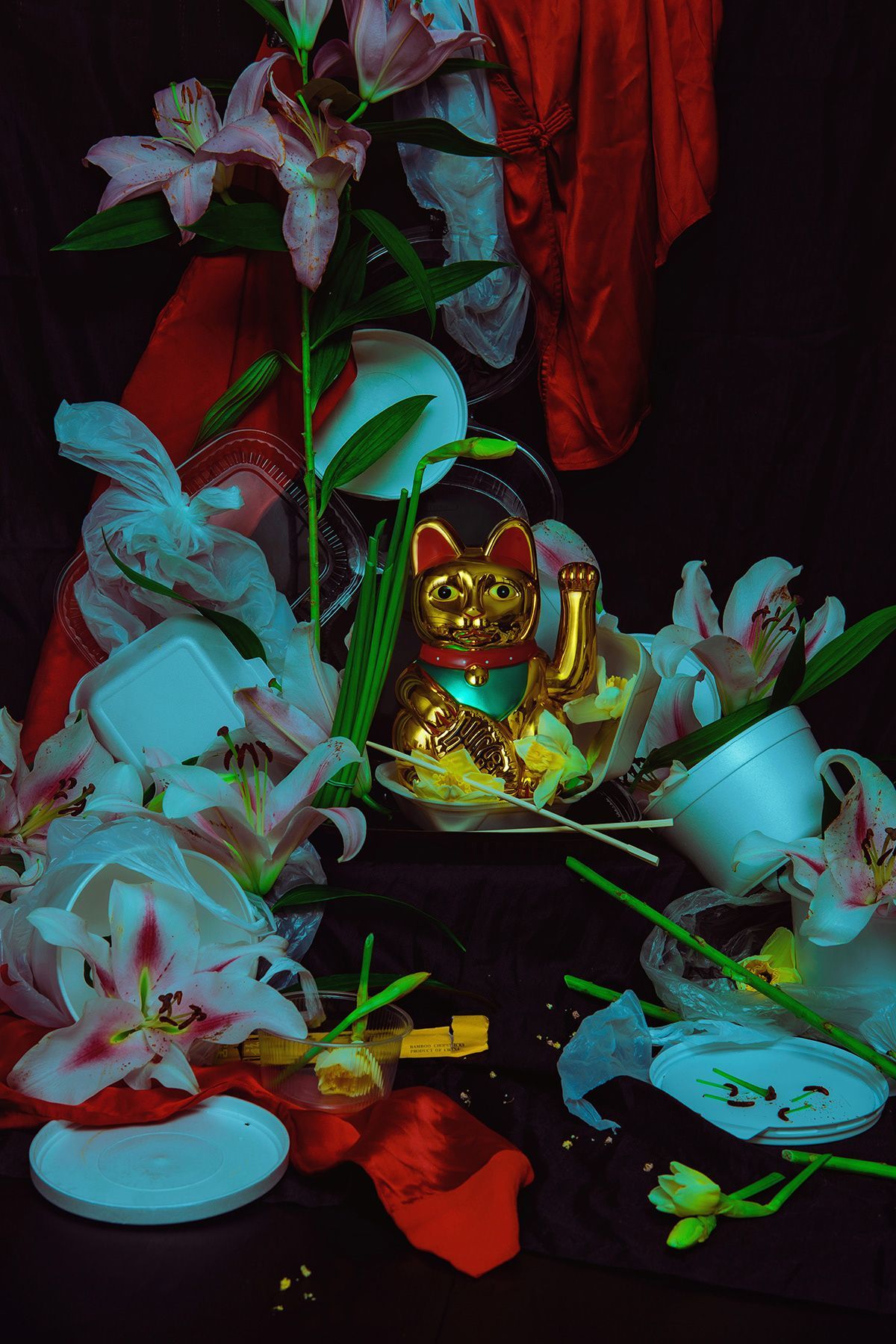 Whimsical still life with pink lilies and lucky cat figurine in neon lighting.
