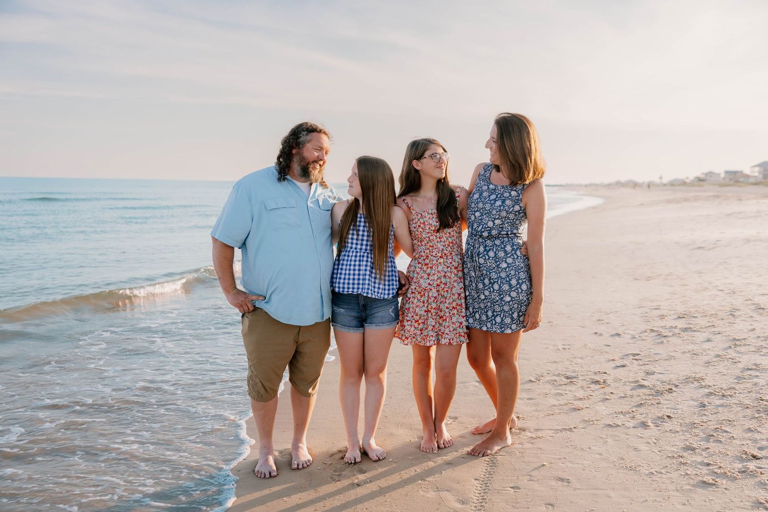 Small group walks together along shoreline at beach during golden hour.