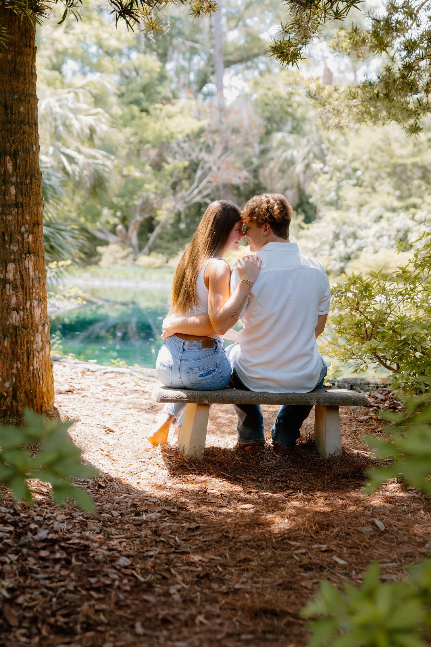 A couple sitting together on a wooden bench in a serene forest setting.