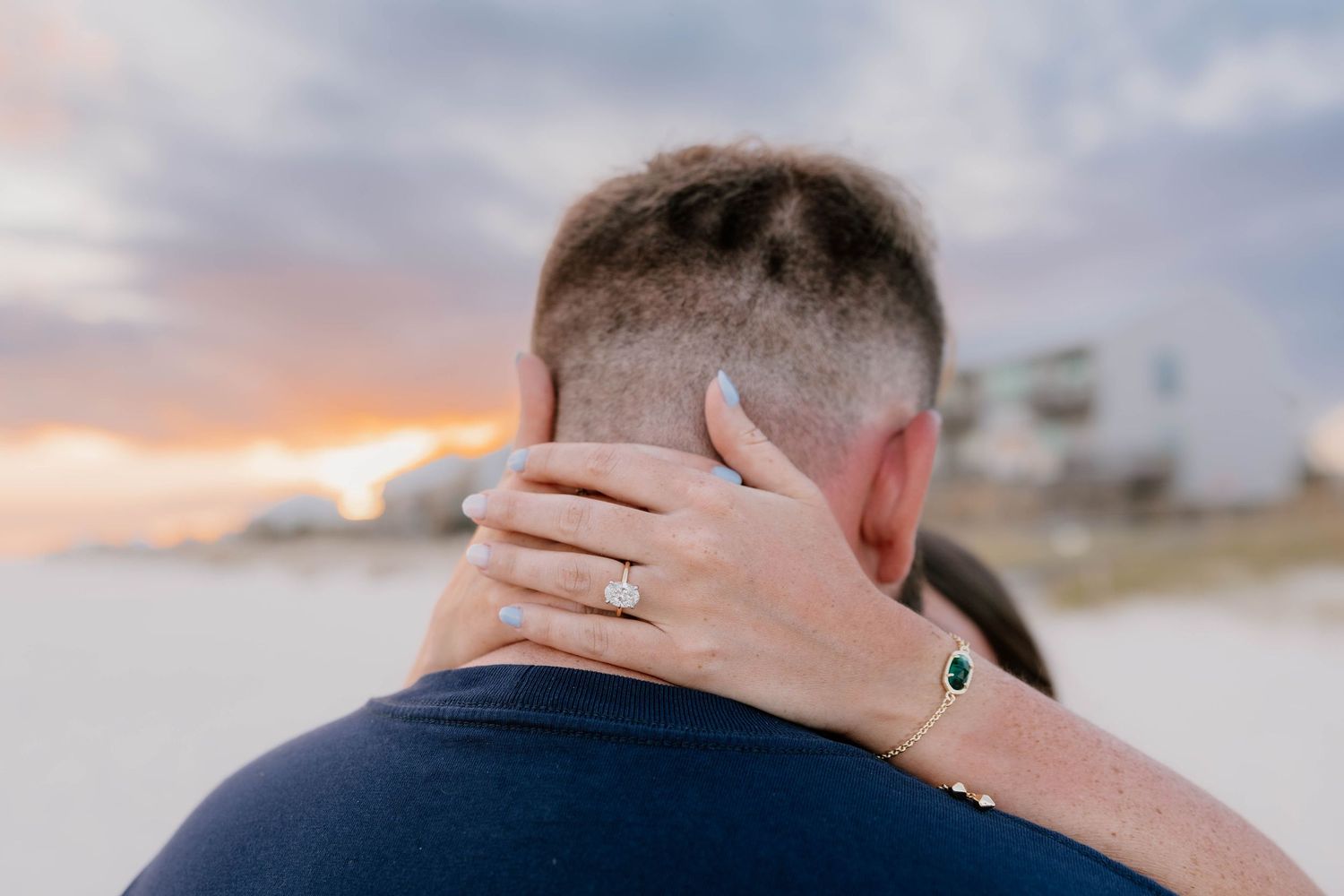 A couple shares an intimate moment on a beach during golden hour with soft sunlight illuminating the scene.