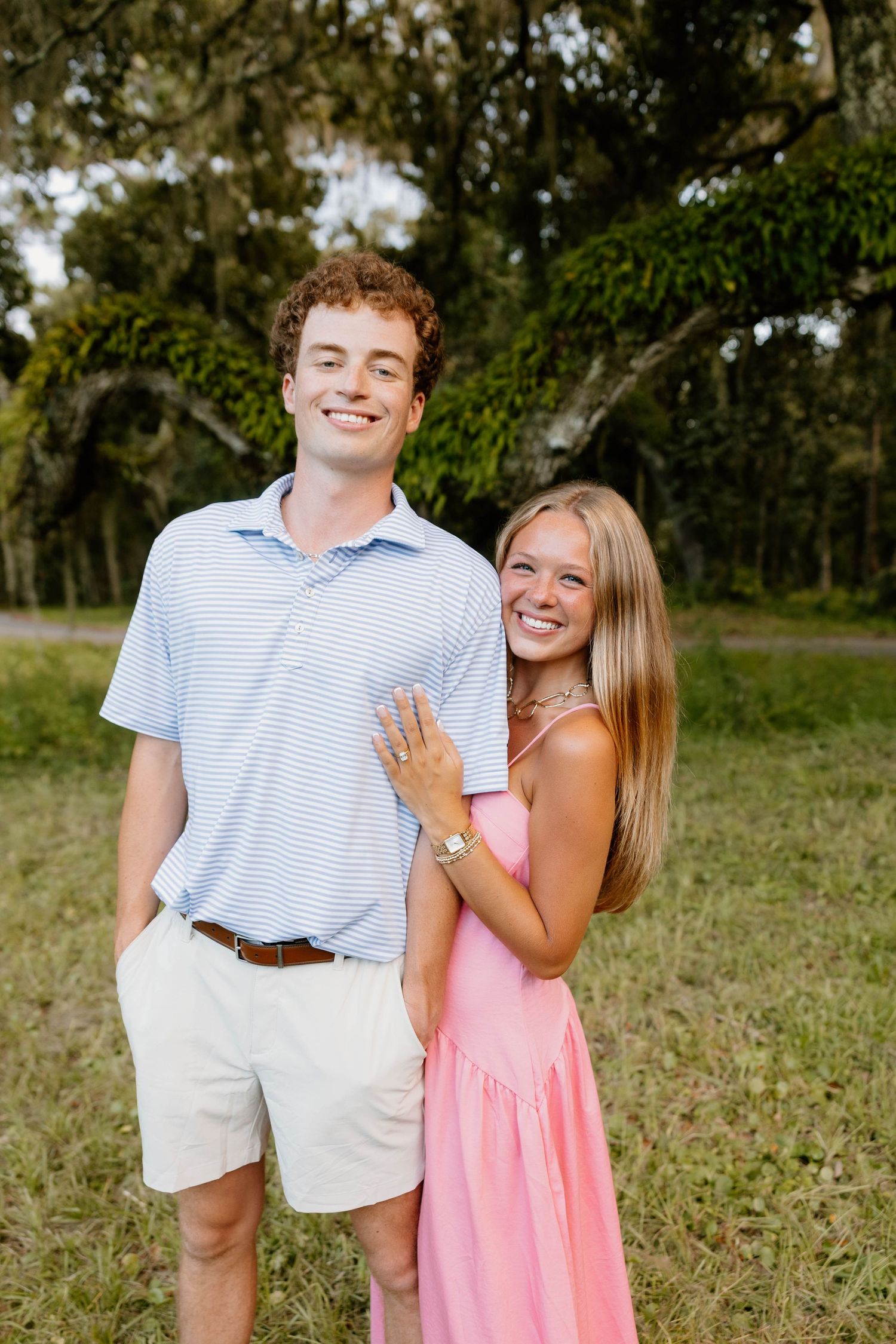 A couple shares joyful laughter together during an outdoor photo session in a grassy field.